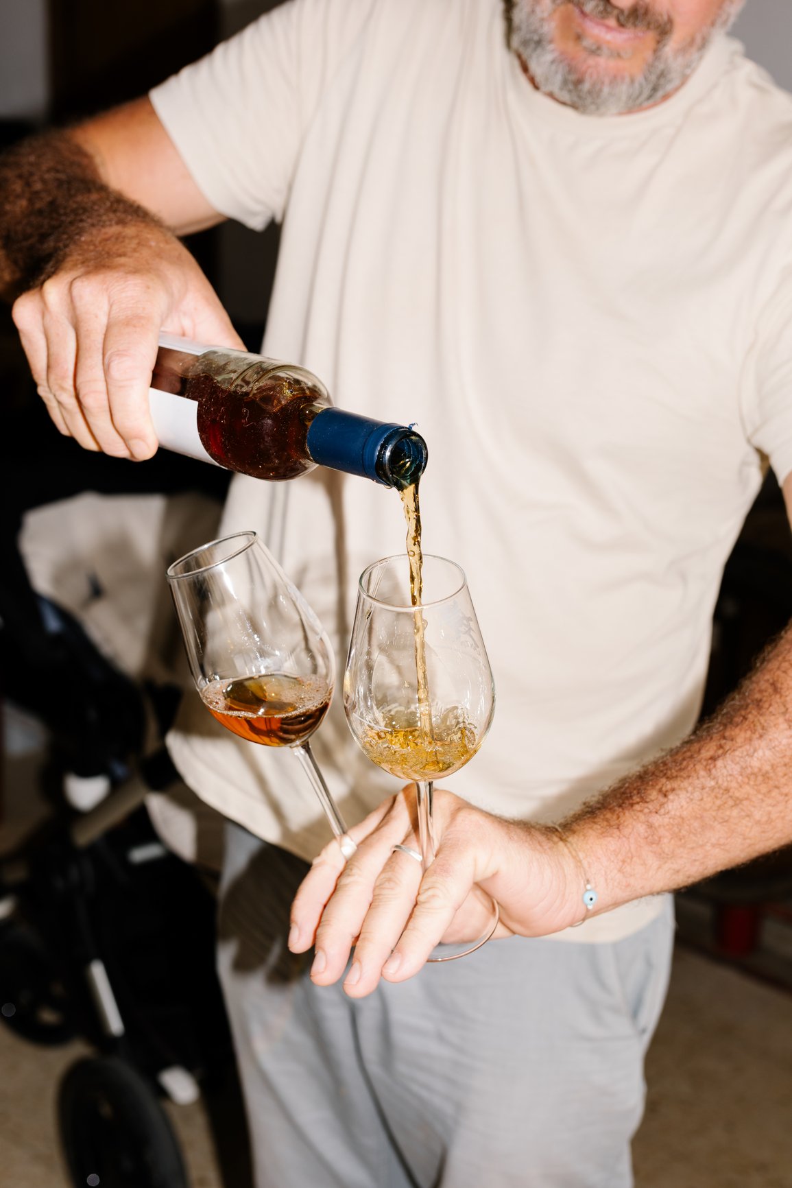 A man pouring red wine from a bottle into a wine glass held by a woman.