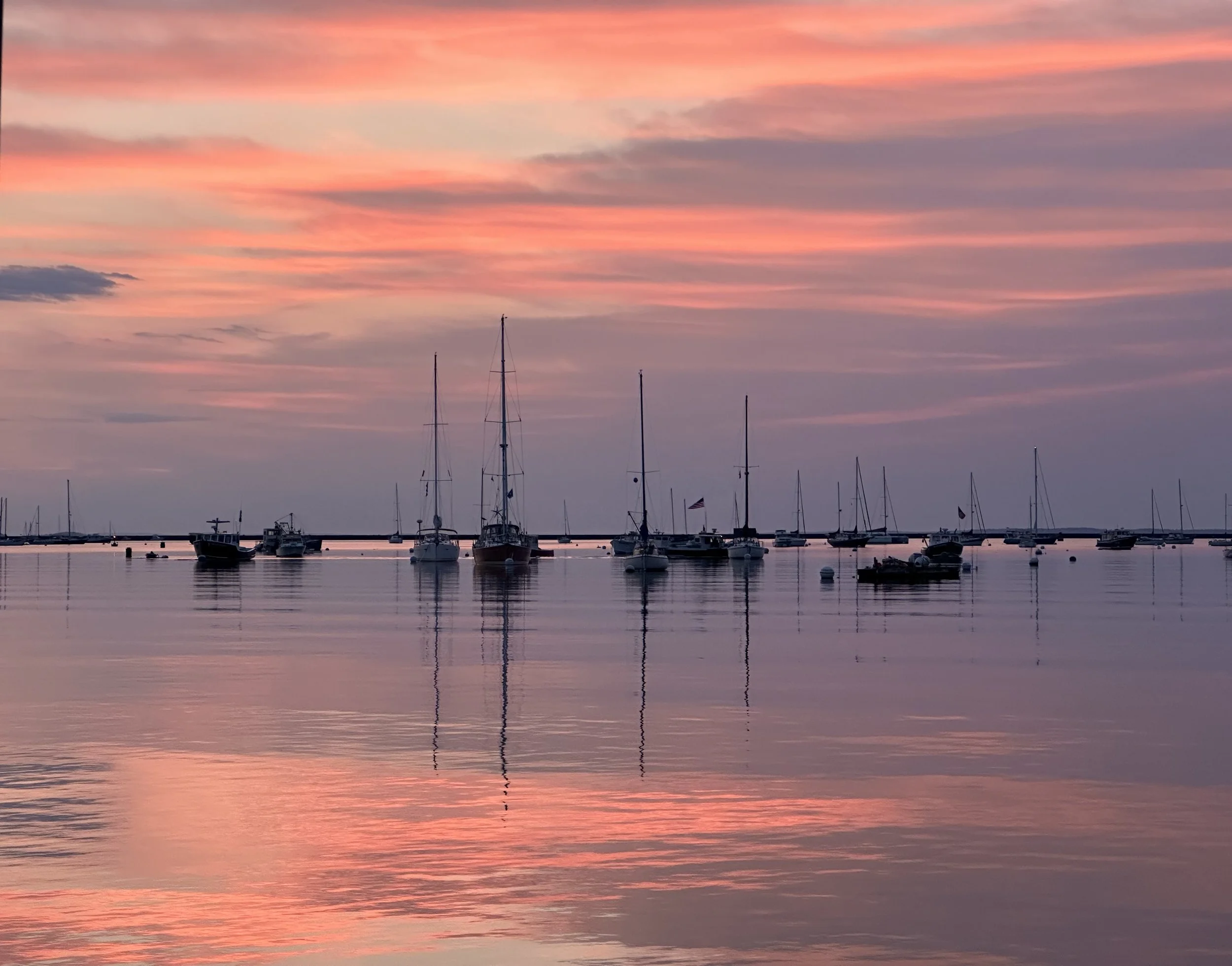 Boats reflected in calm Maine harbor water