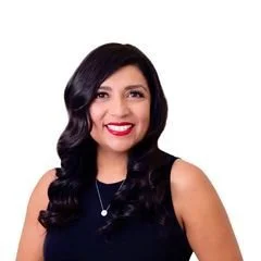 A woman with long black hair wearing a sleeveless black top, smiling with white teeth, against a white background.