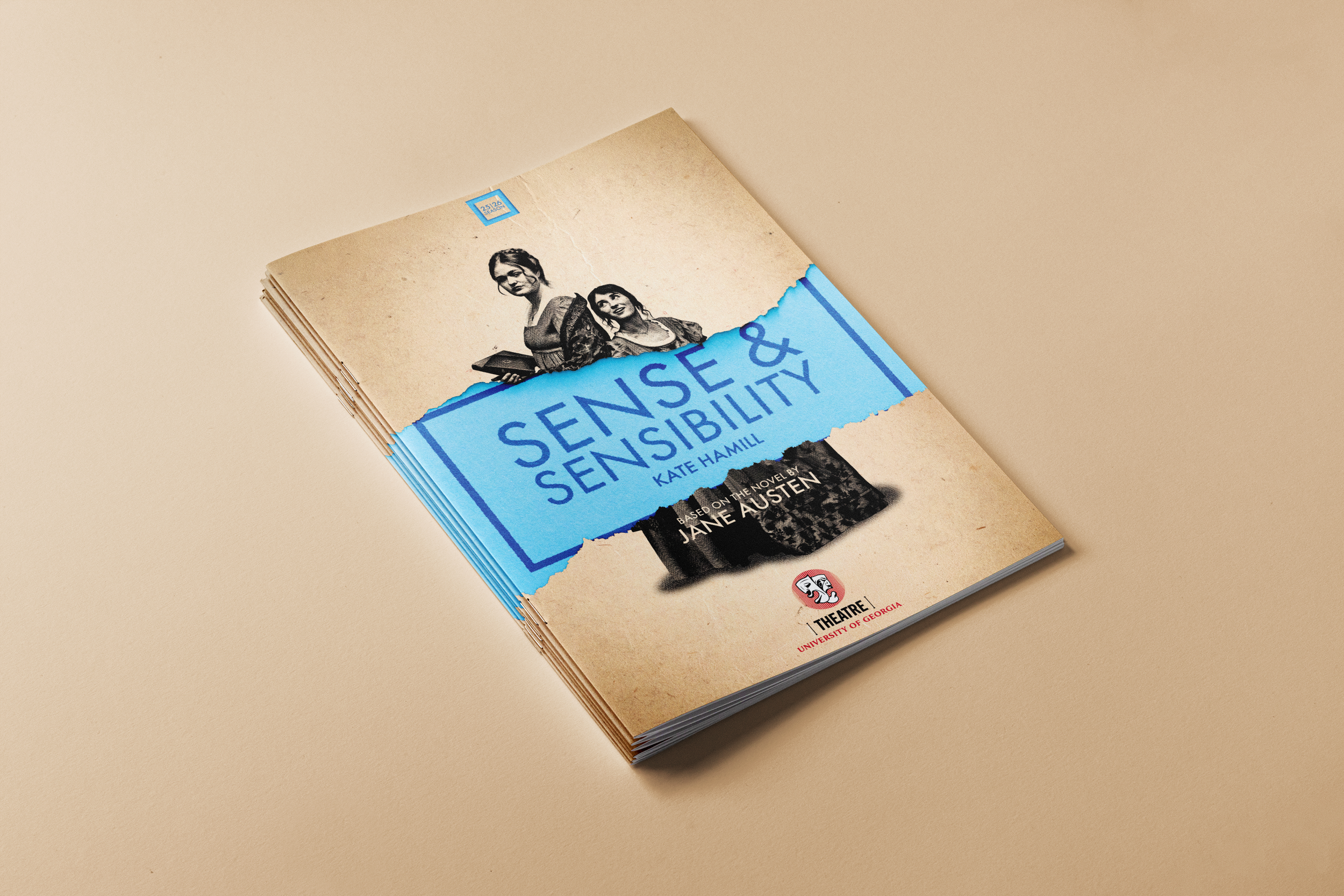 A paperback book titled 'Sense & Sensibility' by Kate Hamill, based on the novel by Jane Austen, lying on a plain beige surface. The cover features a black-and-white illustration of two women, one holding a book, with torn blue paper effect around the title.