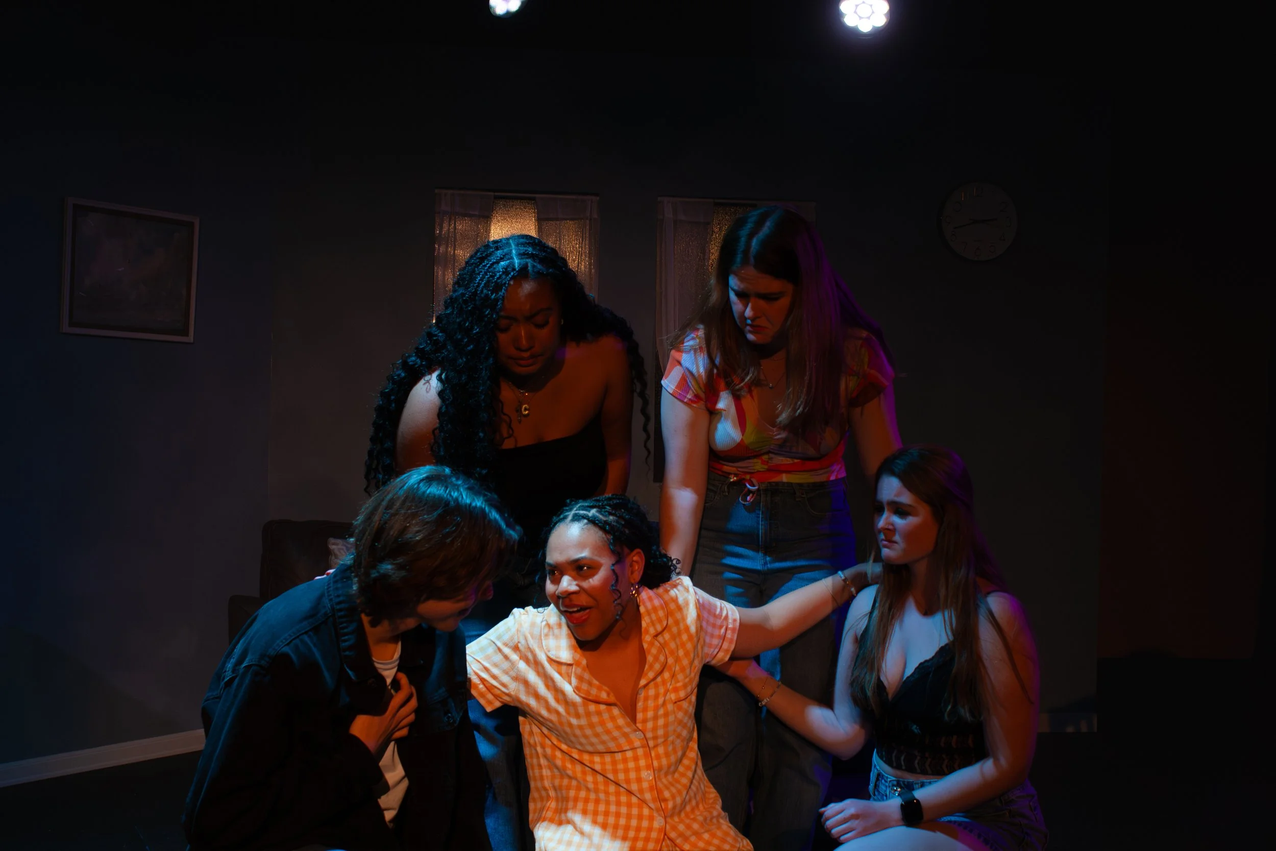 Group of women gathered closely together in a dimly lit room, engaging in conversation and sharing a moment of connection.