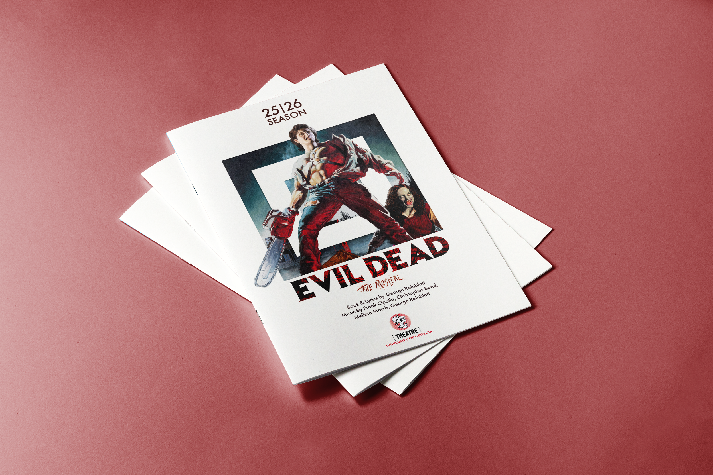 Playbill for the musical Evil Dead on a pink surface, showing a demon-like character with chainsaw, a woman with curly hair, and the title in red letters.