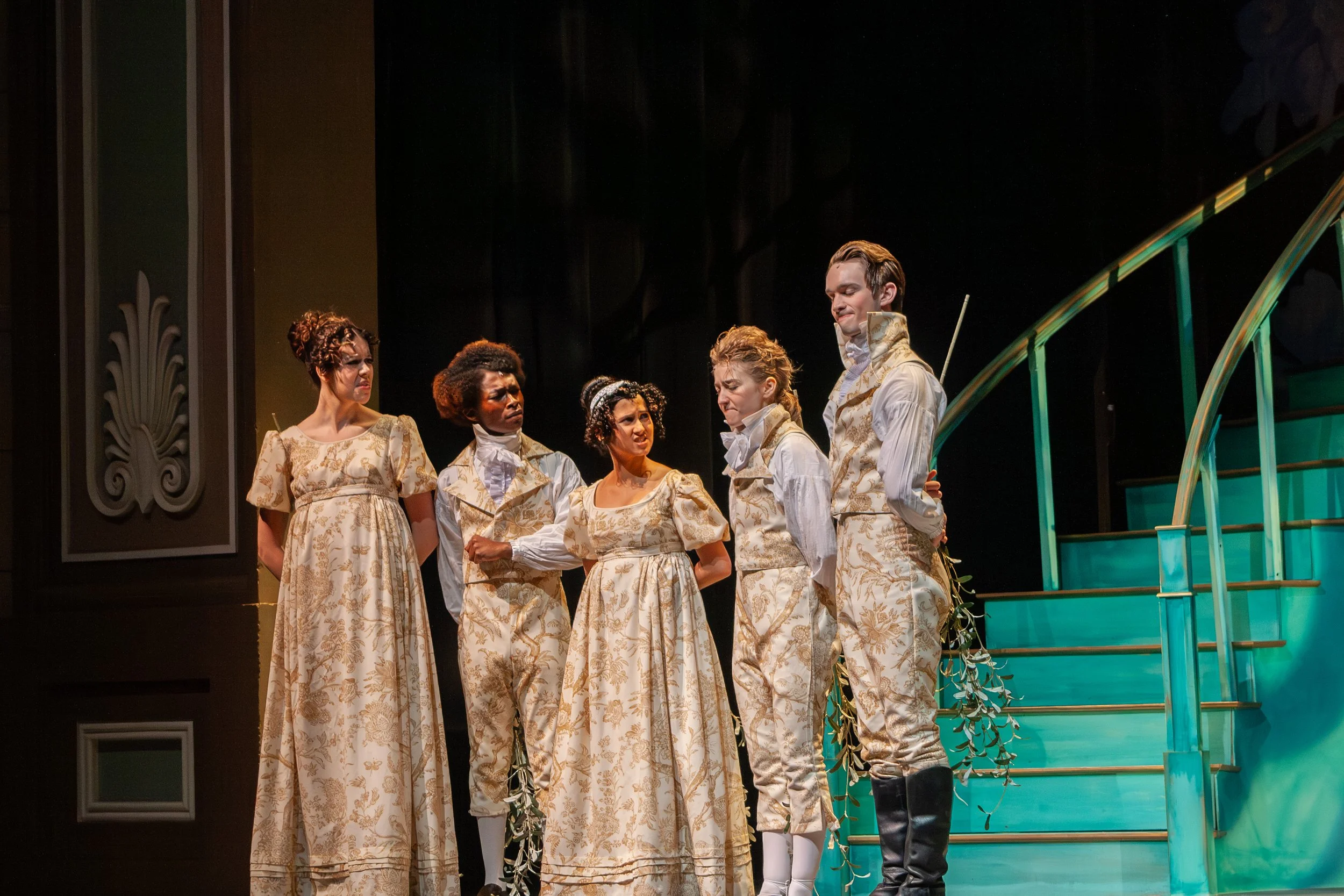 A theatrical performance featuring five actors dressed in period costumes on stage, with some actors appearing emotional, and wooden stairs in the background.