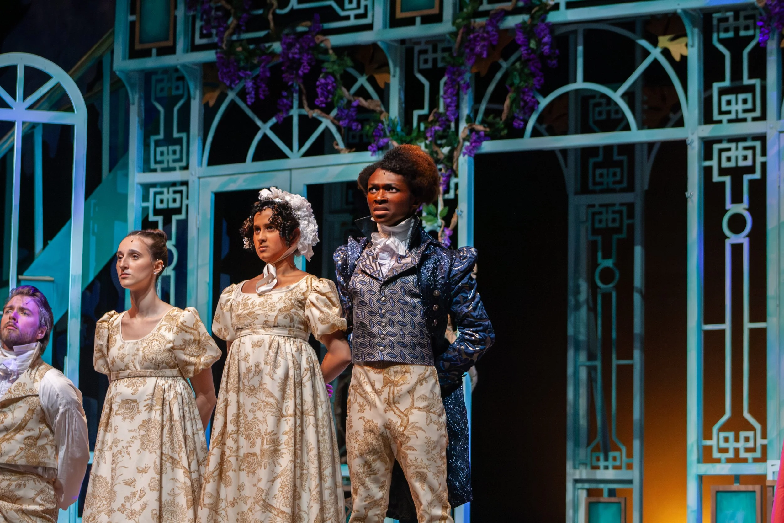 Actors in historical costumes performing on stage with ornate backdrop.