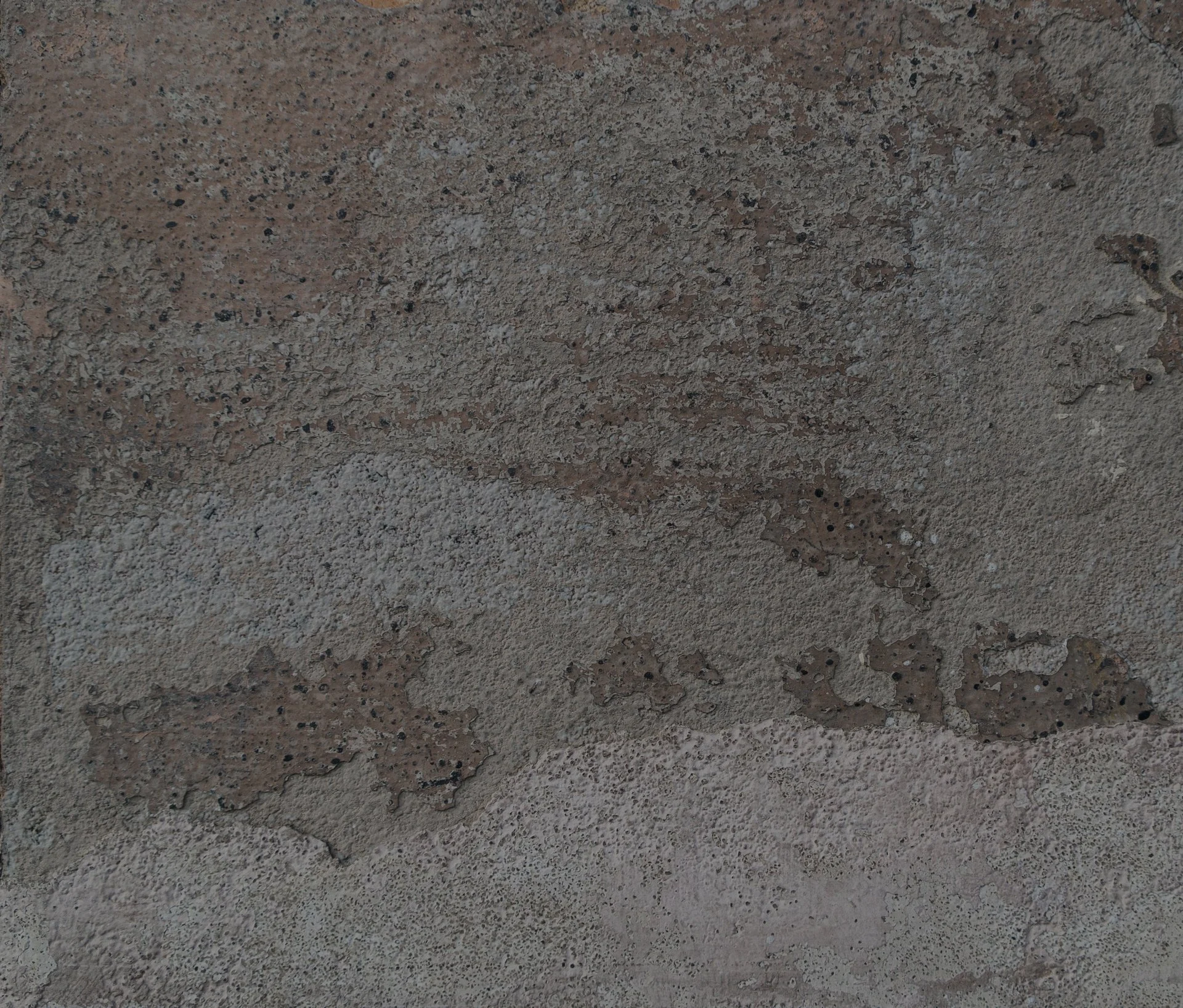 Close-up of a textured, rough concrete wall surface with various small pebbles and cracks.