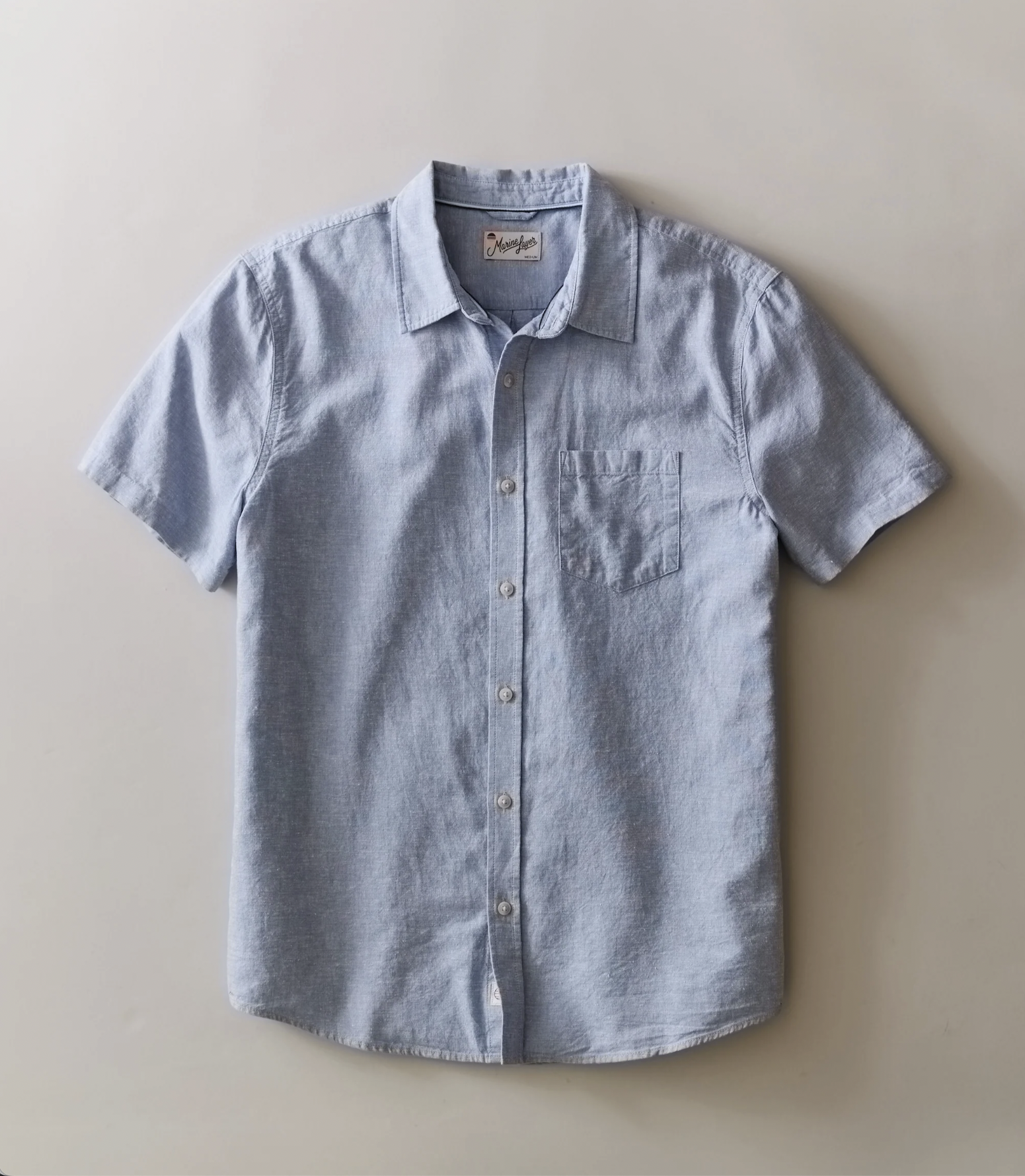 Light blue short sleeve button-up shirt with a chest pocket on a plain white background.