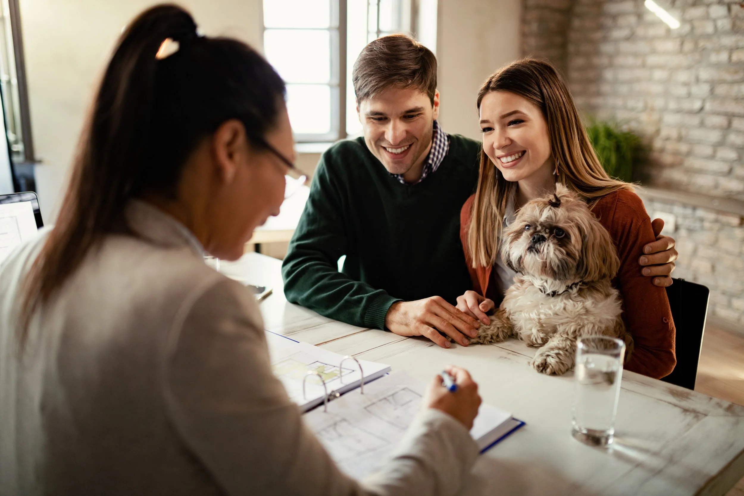 Couple meeting with advisor, holding a small dog.