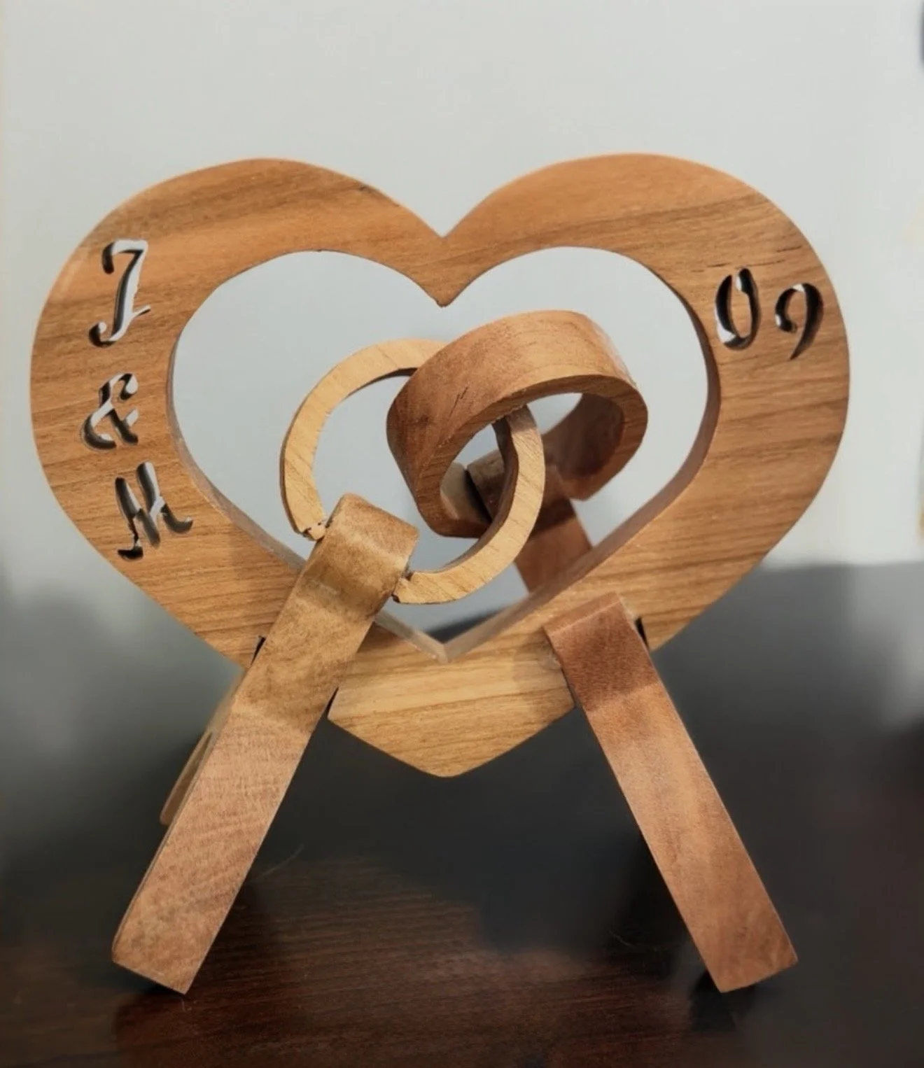 A custom handcrafted wooden anniversary heart sculpture by Bearclaw Woodfixins, featuring personalized initials, a milestone year, and intricate interlocking wedding rings.