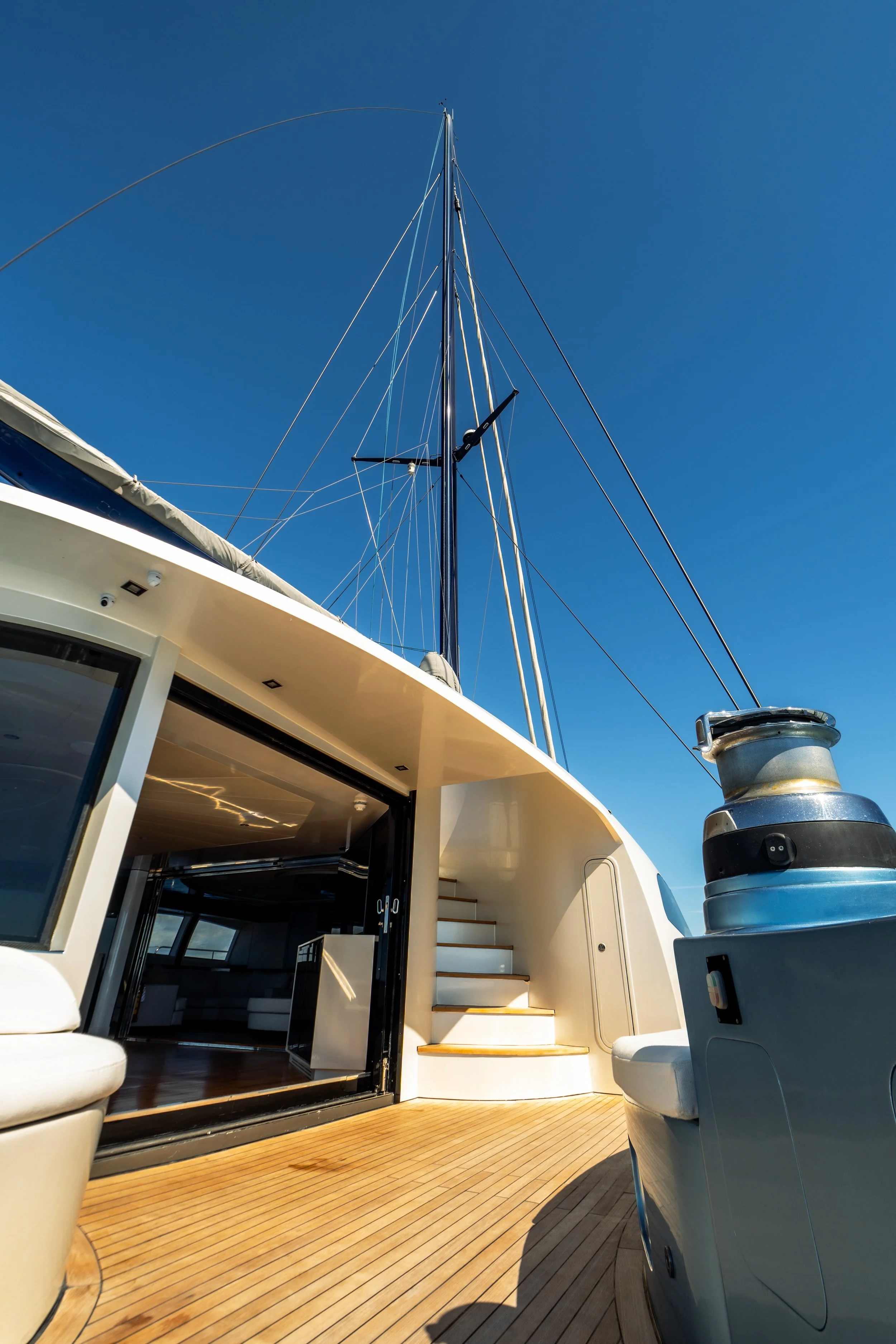 View of the deck on a yacht with a staircase, seating area, and clear blue sky above. LYFE AT SEA
