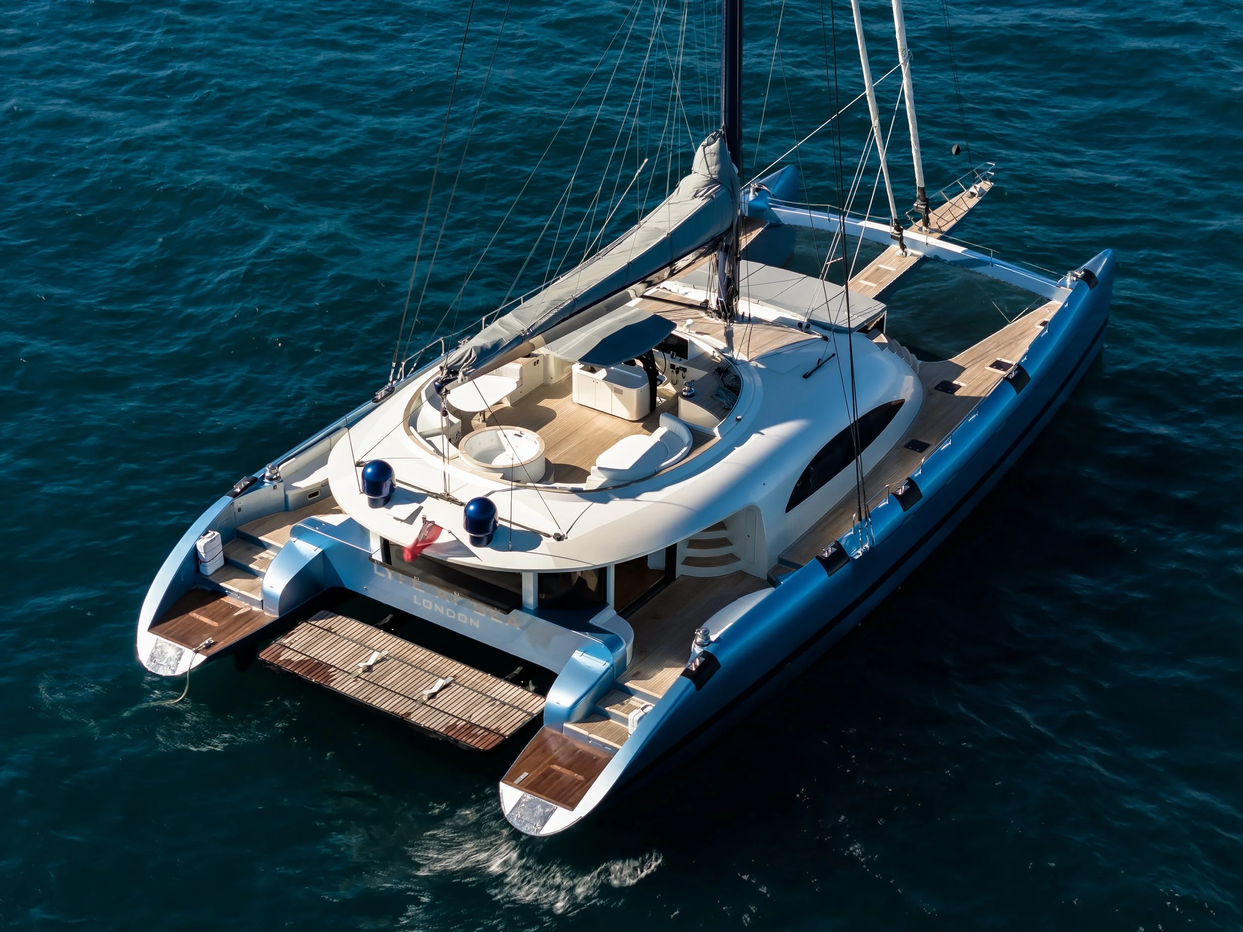 A luxurious white yacht sailing on the open ocean with a sleek design, spacious deck with seating, and a modern control area.