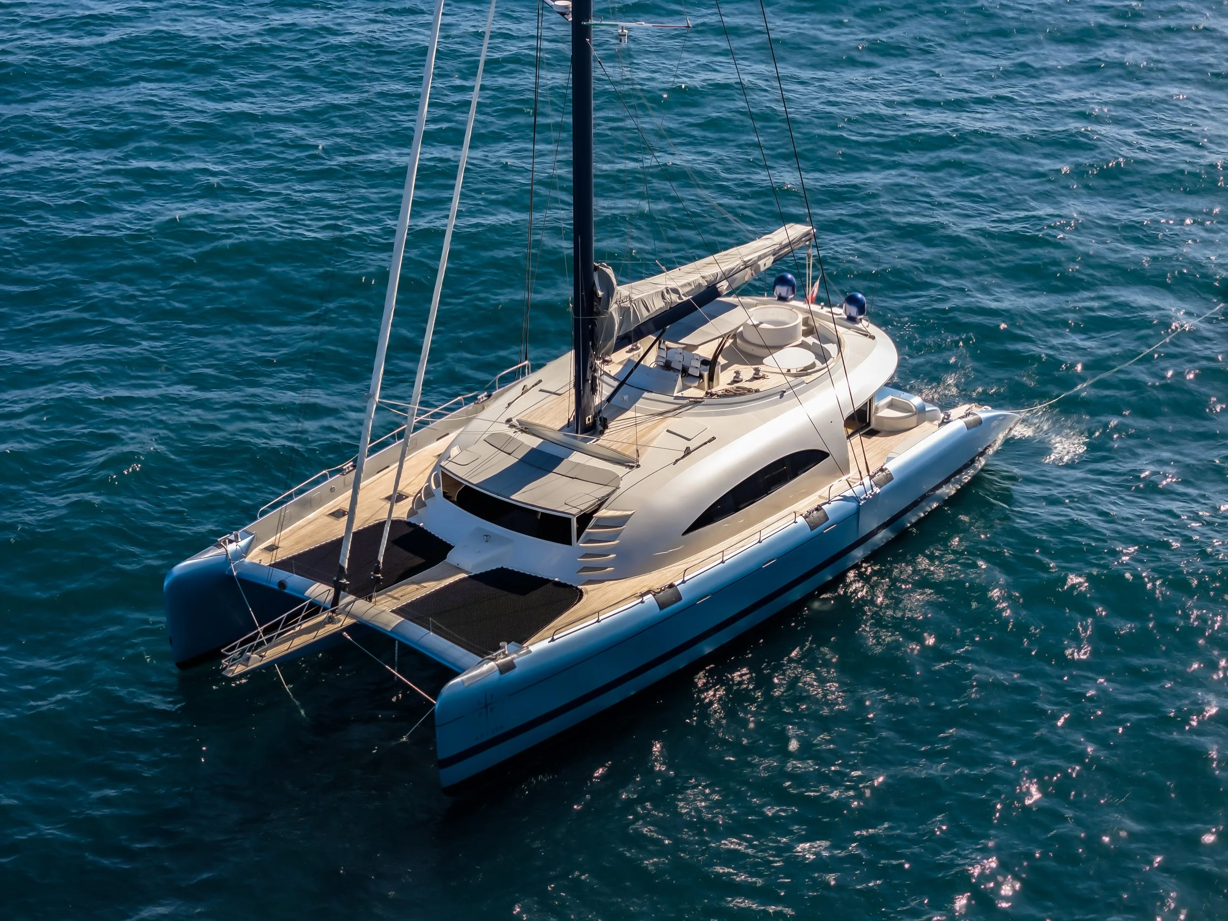 A luxurious white catamaran sailing on calm blue ocean waters under a clear sky. LYFE AT SEA