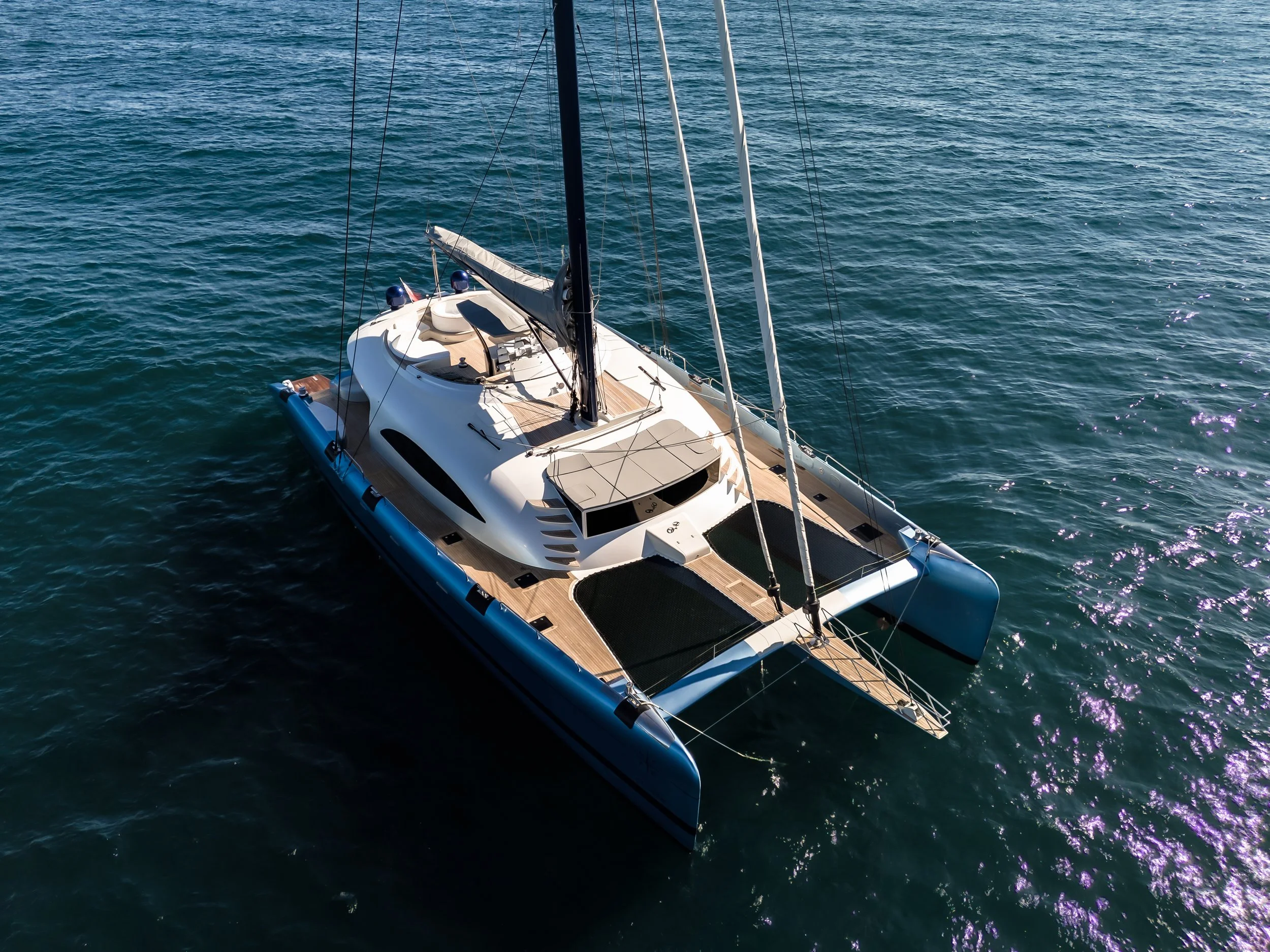 A white luxury sailboat with multiple masts sailing on blue water.