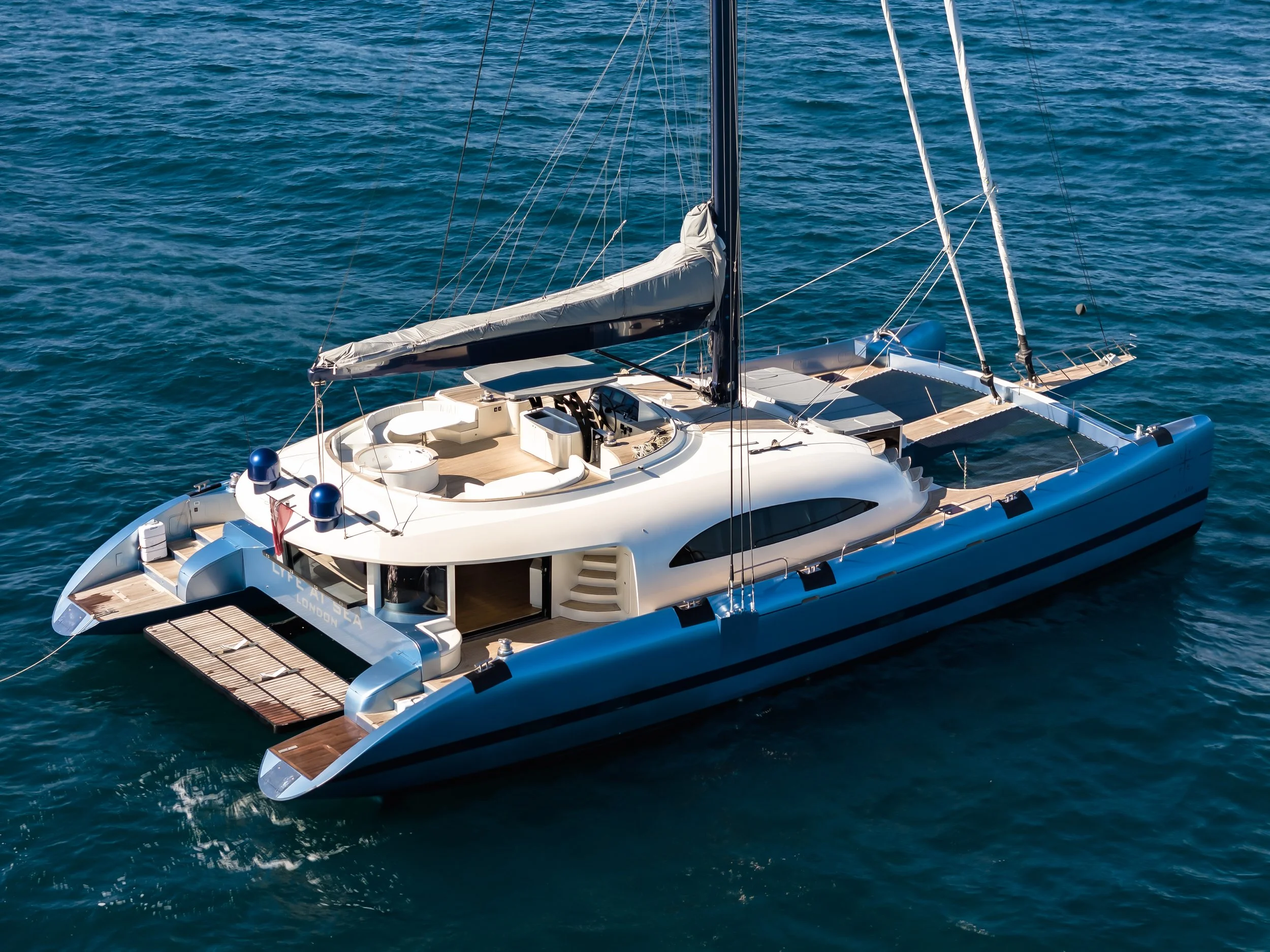 A luxury yacht sailing in the ocean, with a sleek white deck and modern design. LYFE AT SEA
