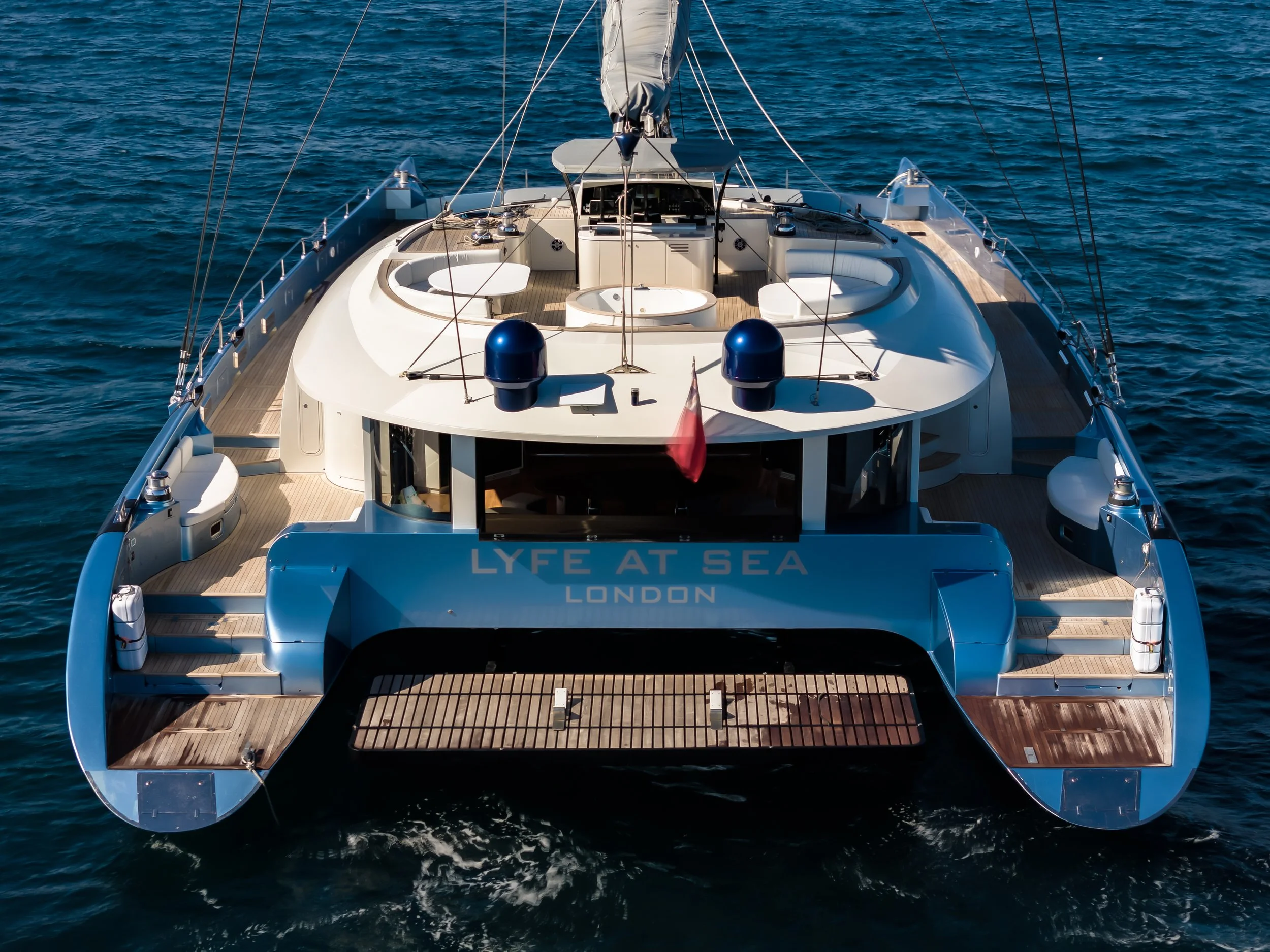 From above view of a modern luxury yacht sailing on the water with a spacious deck and seating area. LYFE AT SEA