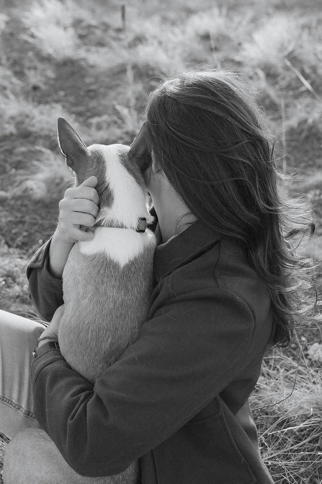 Evelyn Iacono hugging a dog with one arm, with their face close together, outdoors on a grassy area.