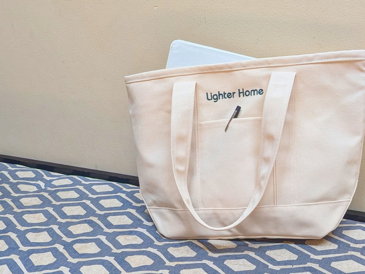 Branded Lighter Home bag on a living room bench with a pen and a binder in it. Working with Lighter Home means that we always know how things work in your home, where things live and what matters most to you.