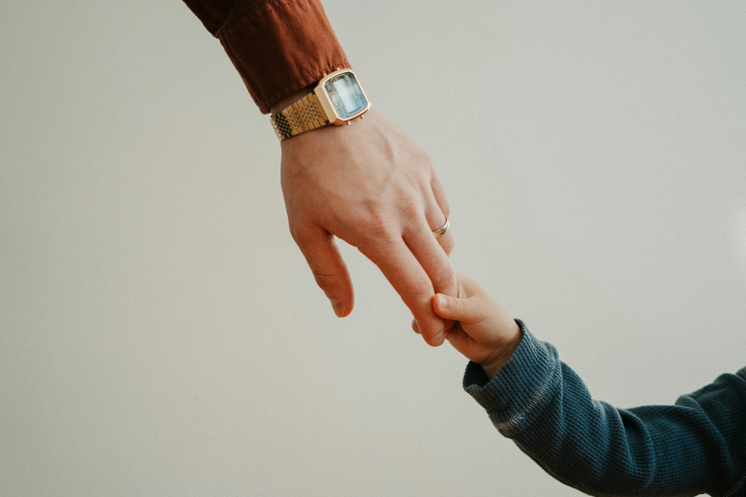 Nahaufnahme eines Erwachsenen, der eine Smartwatch trägt, während ein Kind eine Hand hält.
