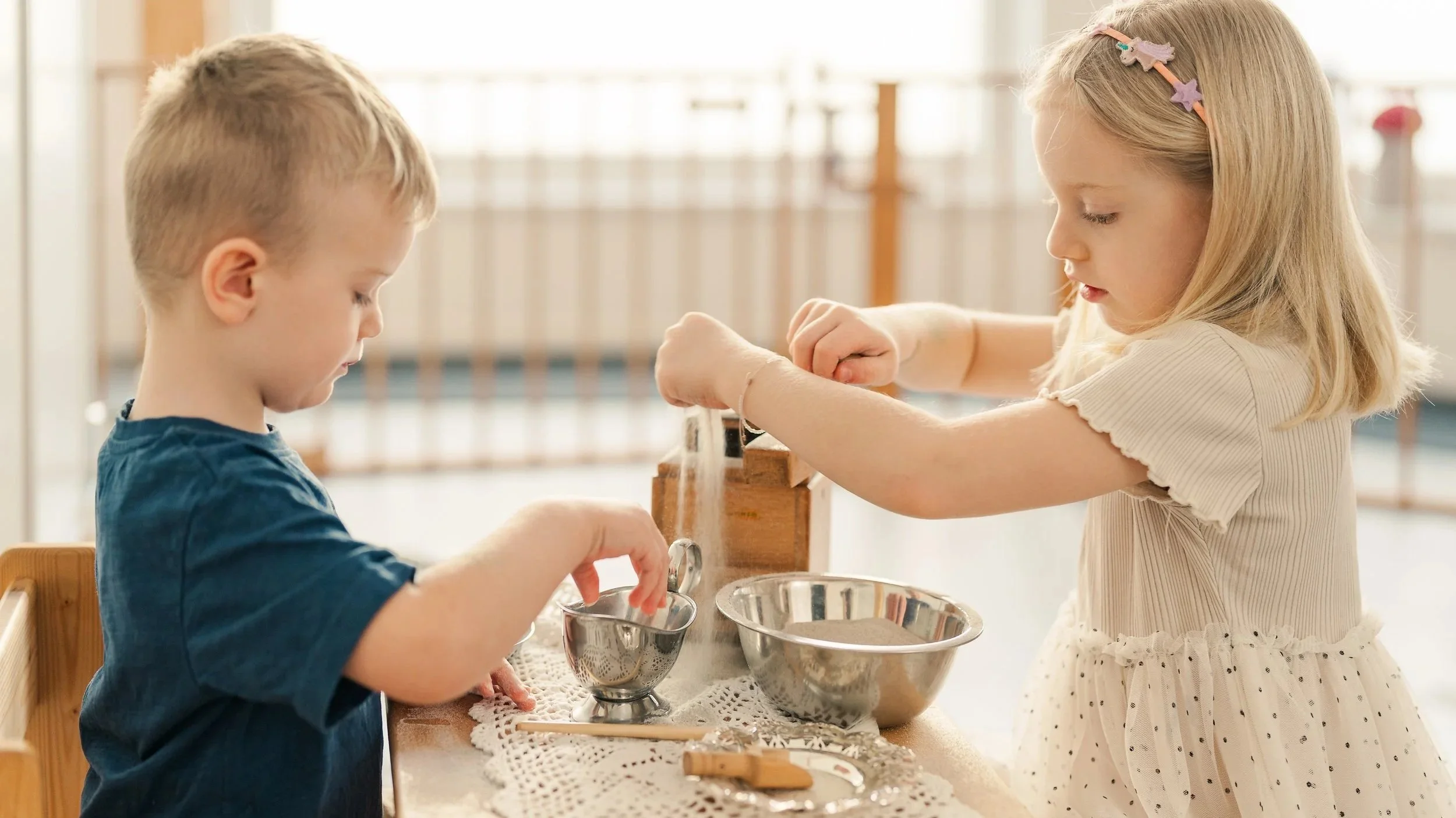 Zwei Kinder, ein Junge und ein Mädchen, backen gemeinsam in einer Küche. Sie bereiten Teig vor und verwenden verschiedene Schüsseln.