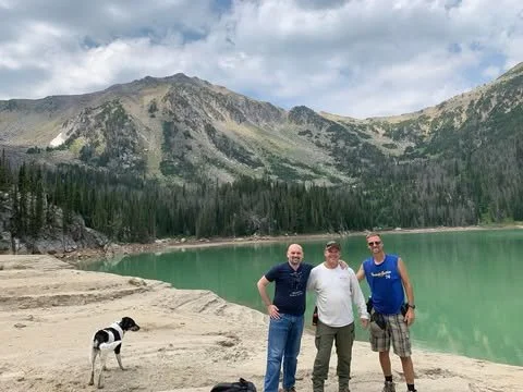 Three men and a dog by a lake