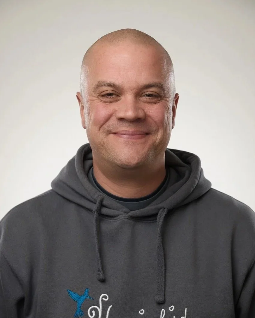 Staff member Steve smiling, wearing a dark hoodie with a hummingbirds logo