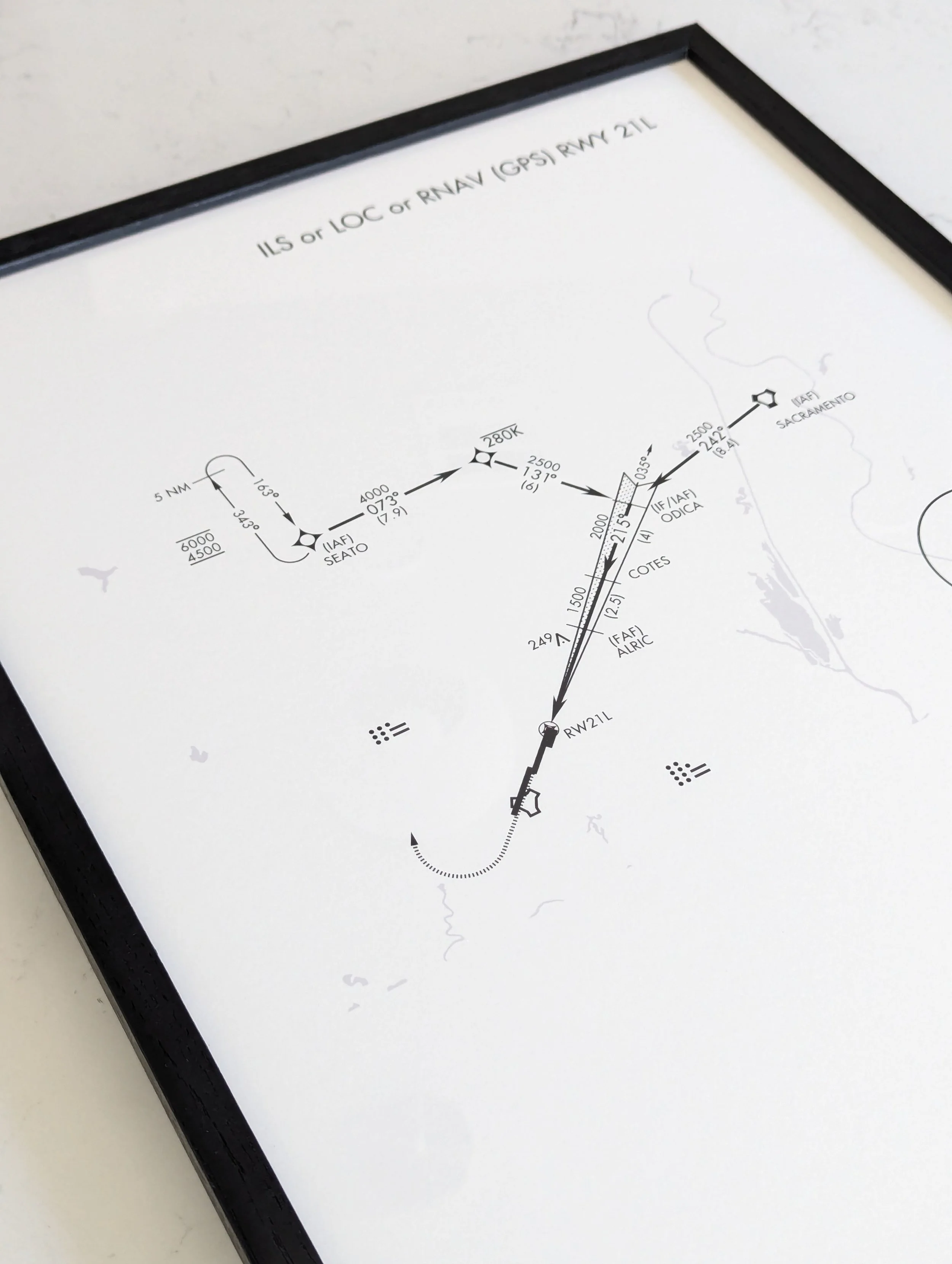 Close-up product photograph of Decision Height Archival Timber print showing the high-contrast monochrome aviation chart printed on 250 gsm matte paper, encased in a solid black wooden gallery frame with clear protective plexiglass.