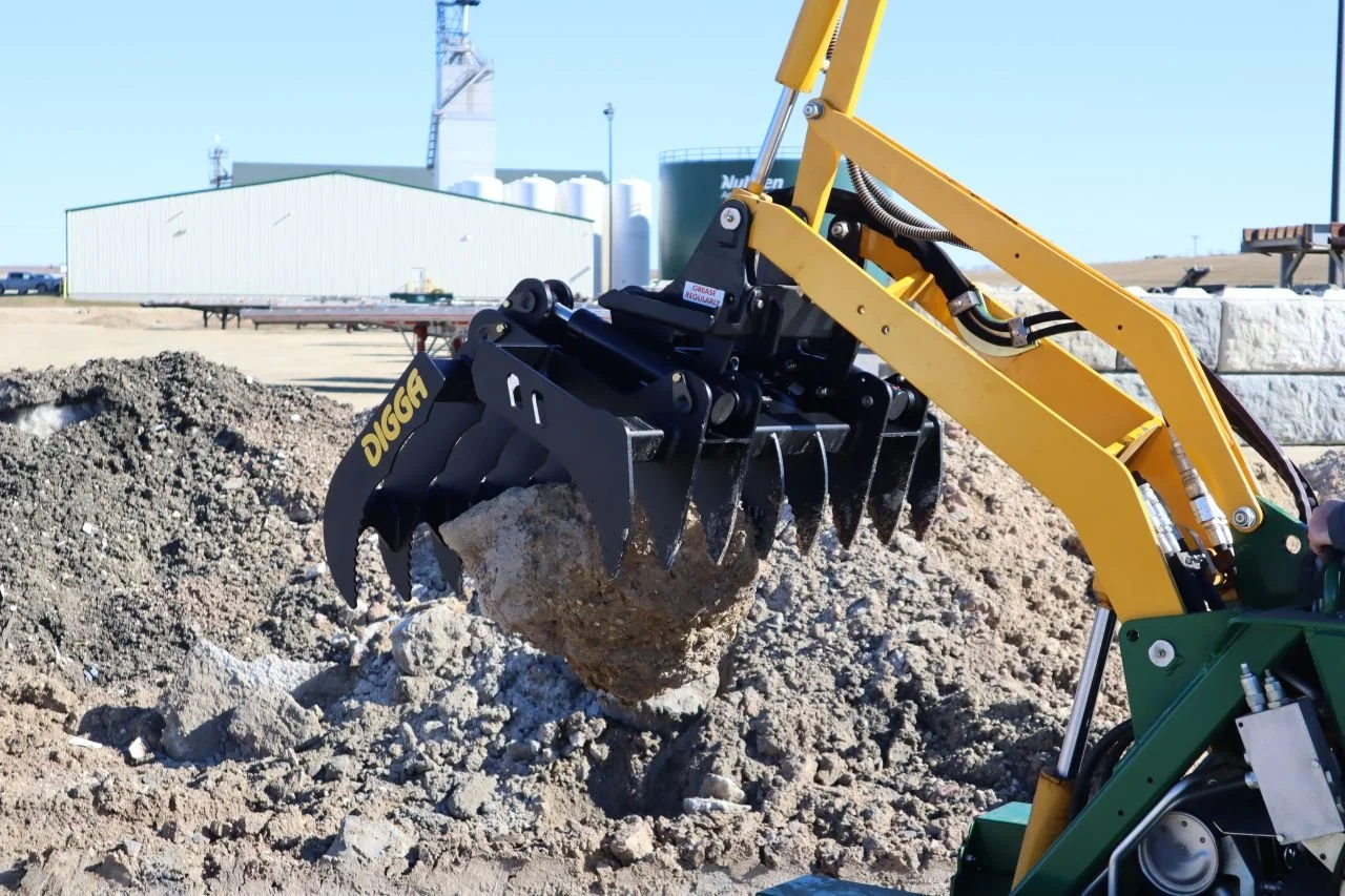 A yellow and black mini excavator digging into dirt on a construction site.