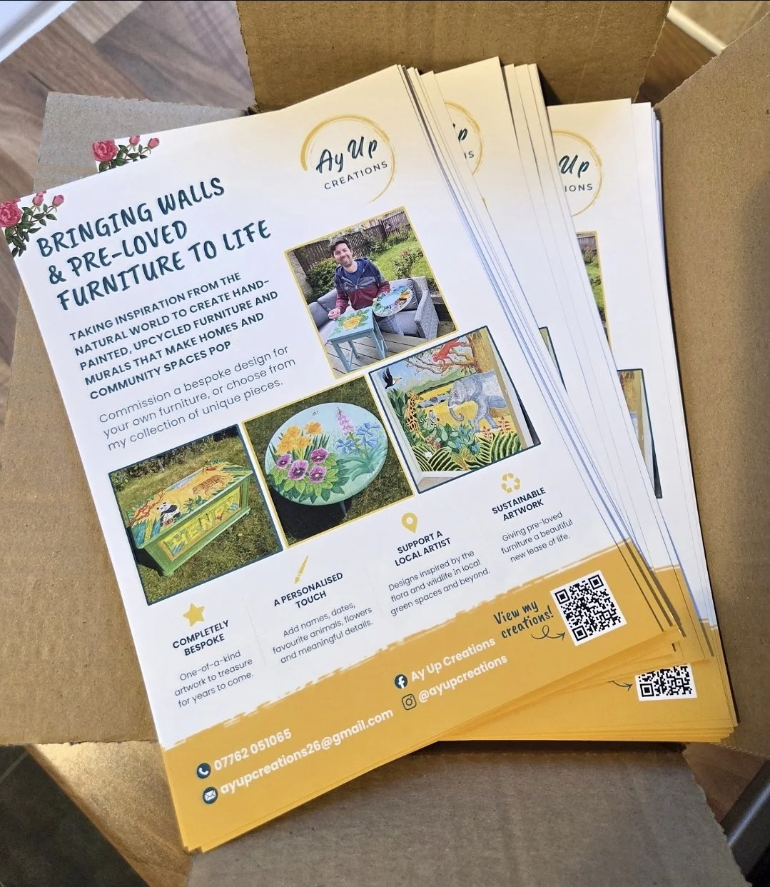 A stack of flyers from Ay Up Creations promoting custom furniture and murals inspired by nature. The flyer features images of painted furniture, murals, and an artist, with contact information and social media handles at the bottom.