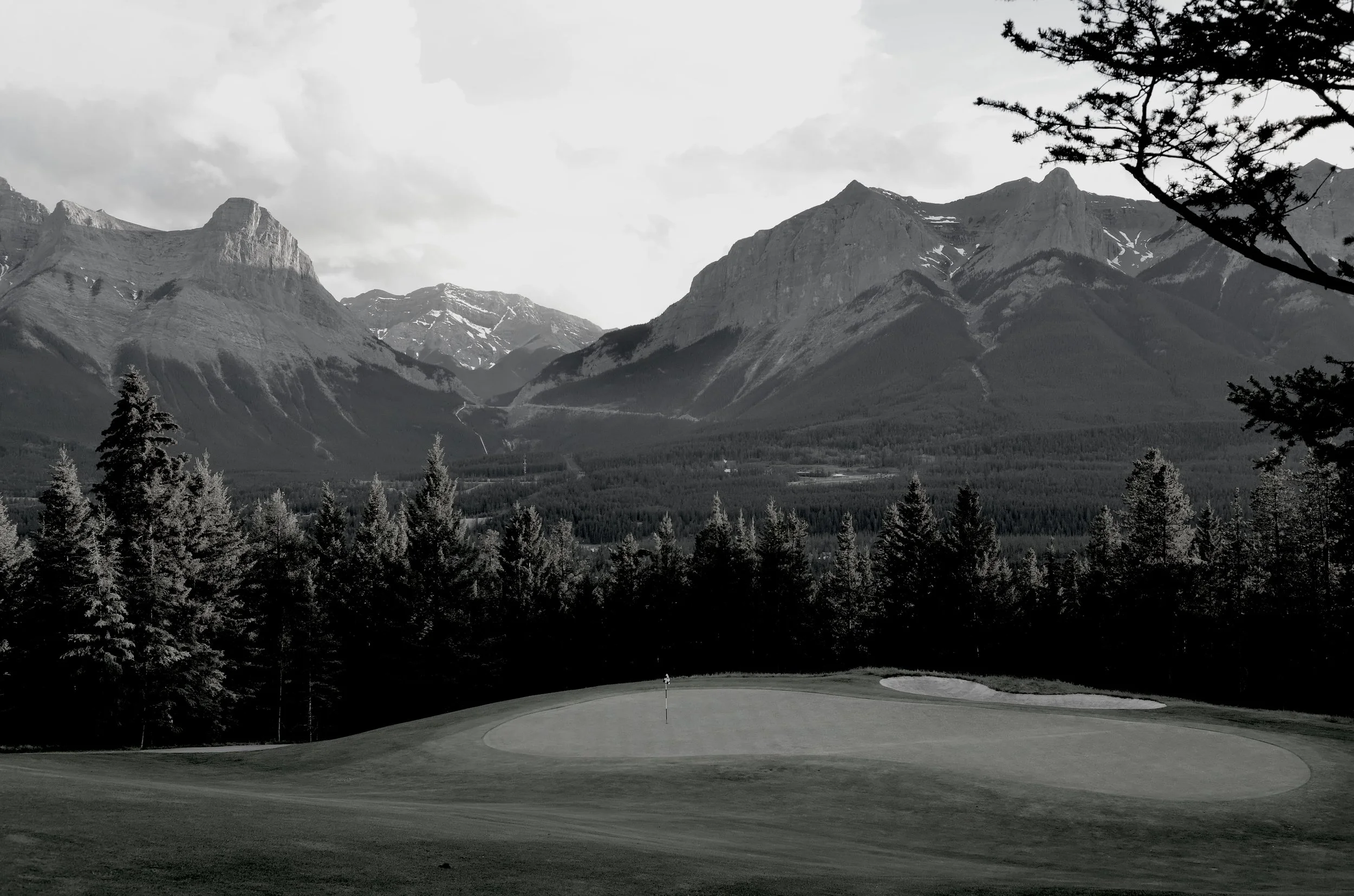 Early morning shadows across a golf course beneath the mountains.