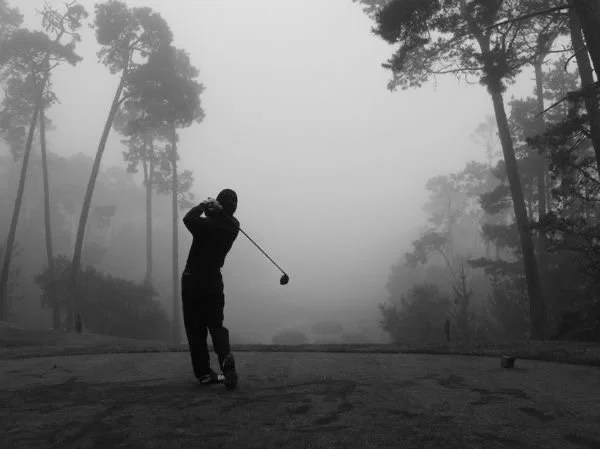 Golfer teeing off in the fog