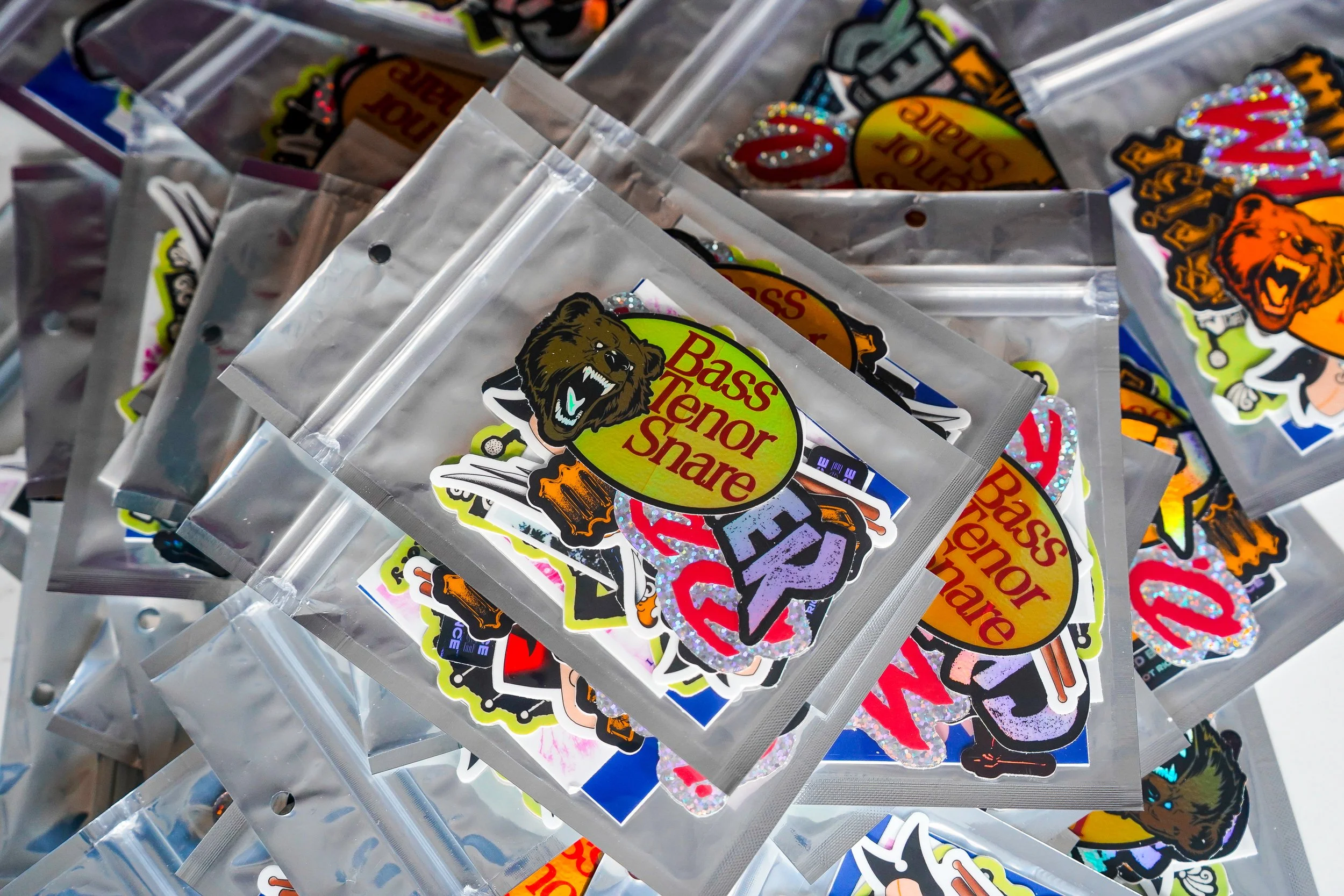 Assorted stickers with brand logo 'Bass Terror Share' featuring a bear head, and other colorful designs in clear plastic packaging.