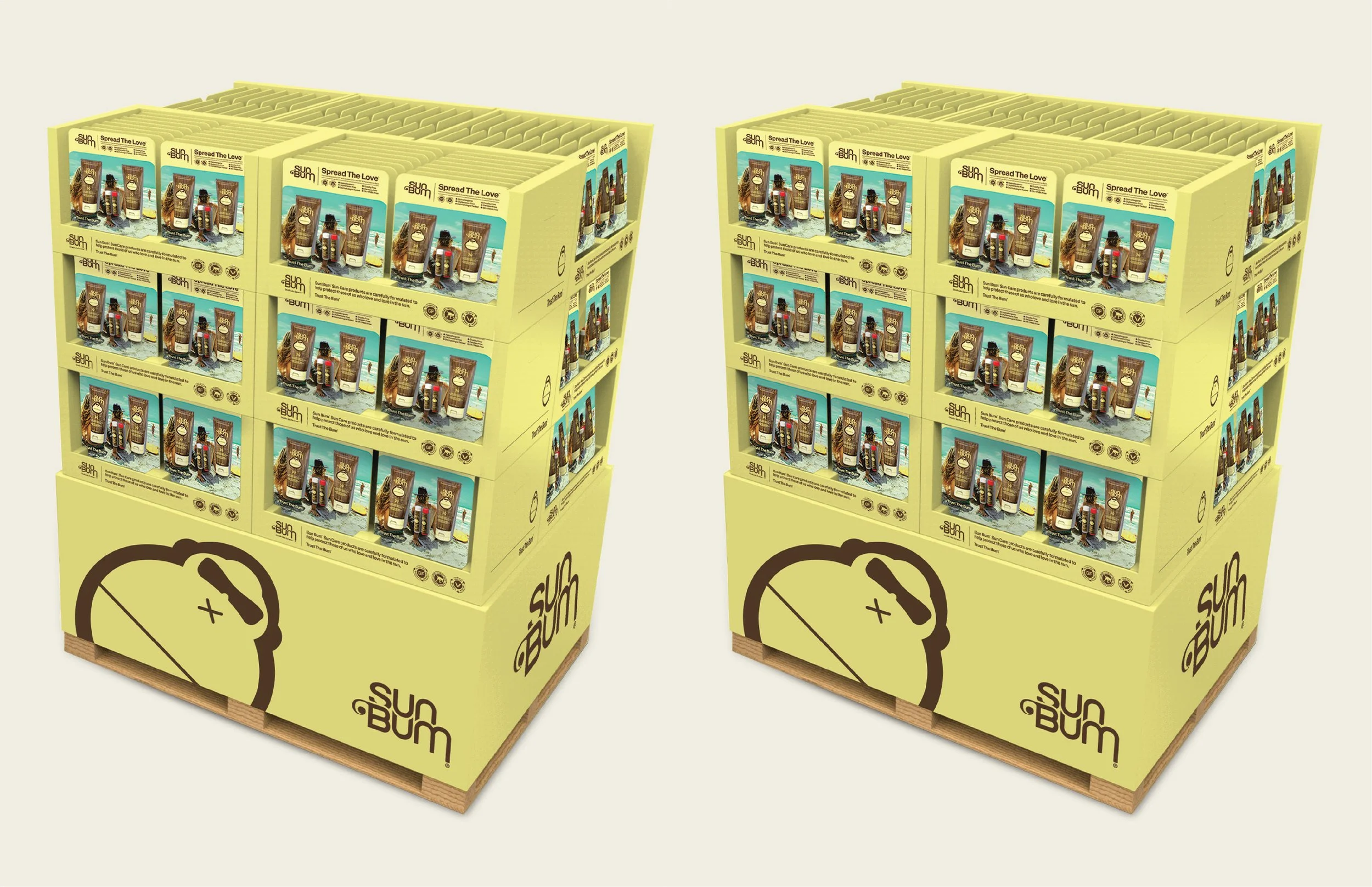 Stacked boxes of Sun Bum sunscreen on a wooden pallet, with yellow packaging featuring a cartoon brain logo, displayed in a retail setting.