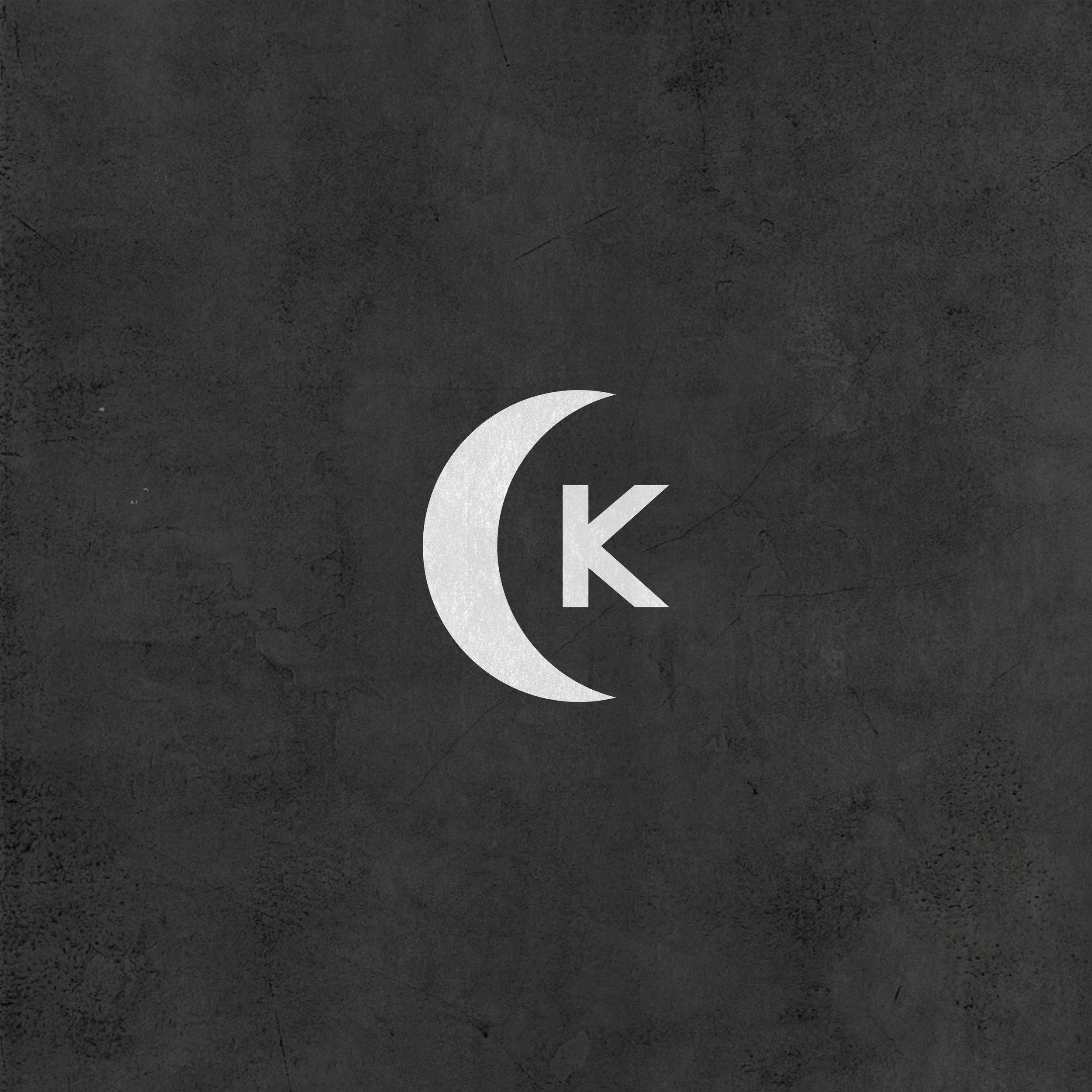 Close-up of a gray textured background with a partial white crescent moon and the letter 'K'