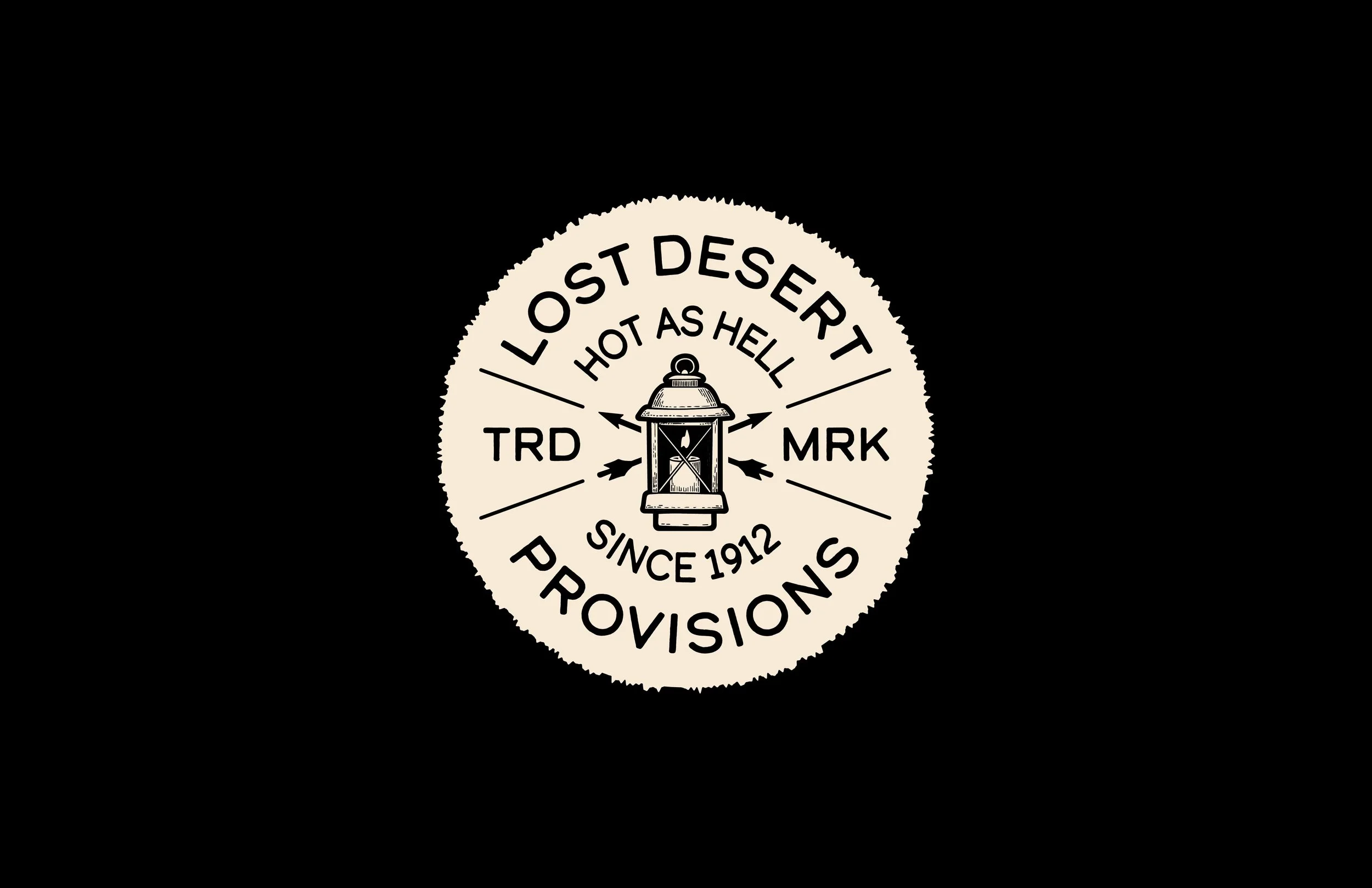 A circular badge with text and a lantern illustration, reading 'Lost Desert Hot As Hell Since 1912 Producing'.
