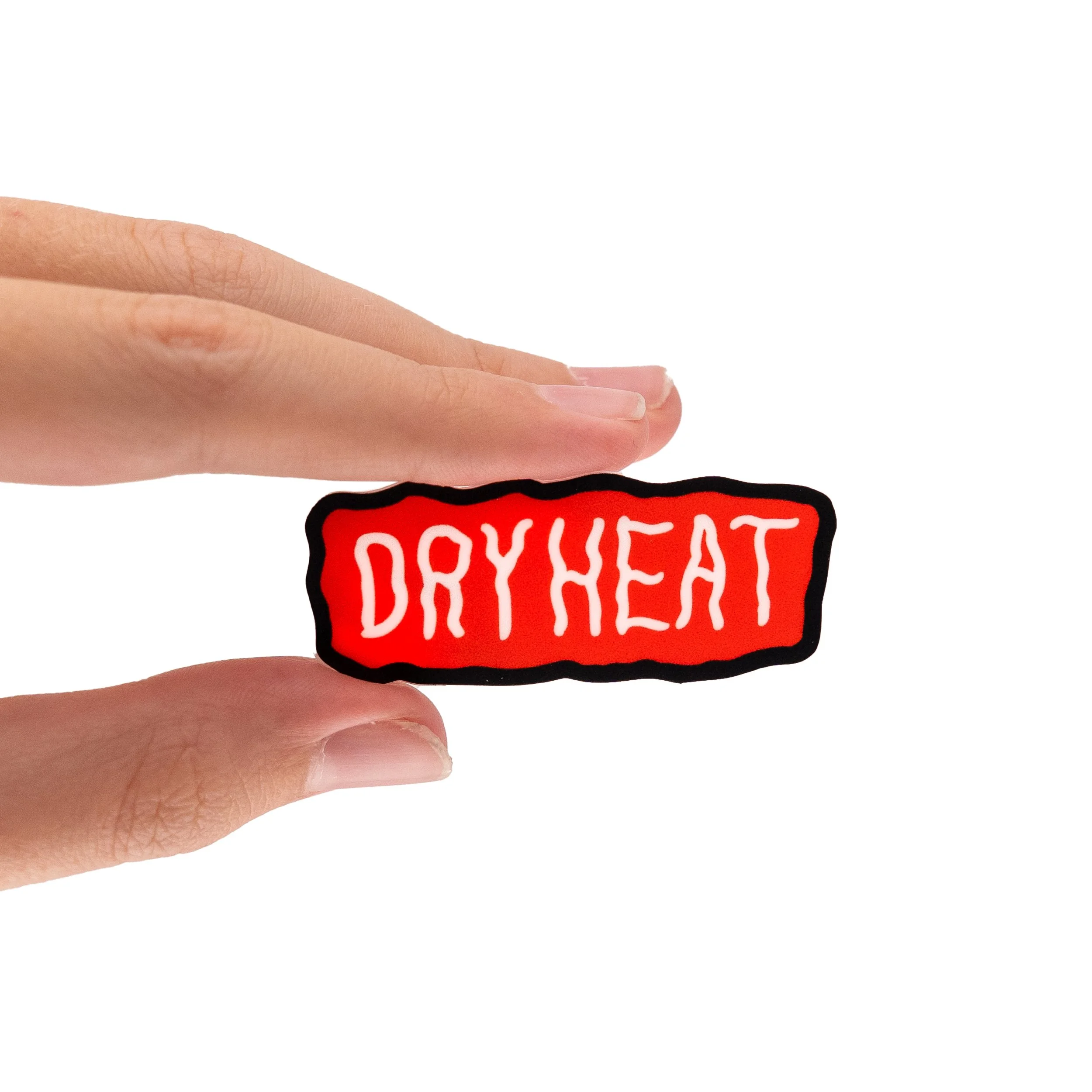 Close-up of a person's hand holding a sticker with a red background and white text that reads "DRYHEAT".