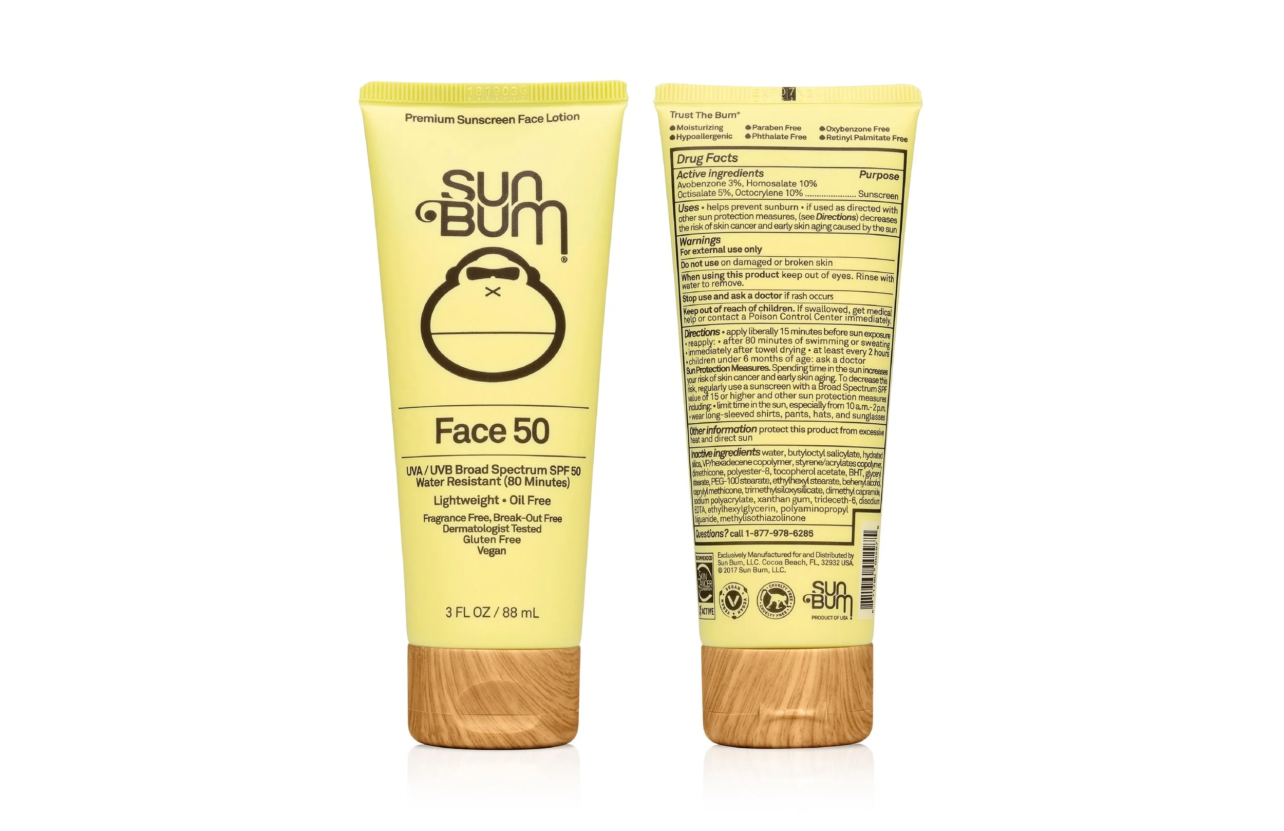 Yellow tube of Sun Bum Face 50 sunscreen with black text and a black outline of a face with sunglasses, resting on a wooden surface, with detailed product information on the back of the tube.