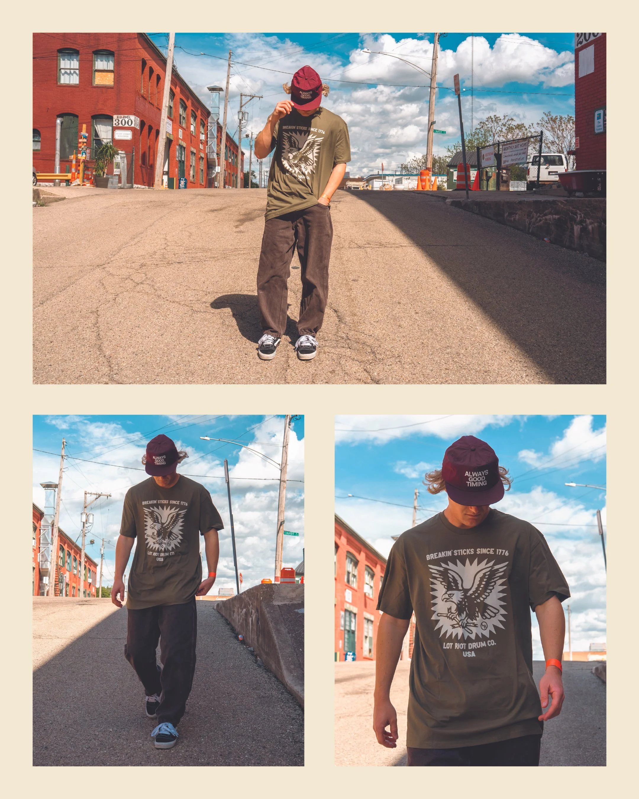 A young man walking down a street with red brick buildings, power lines, and a blue sky with clouds behind him. He wears a baseball cap, a graphic t-shirt, dark pants, and sneakers.
