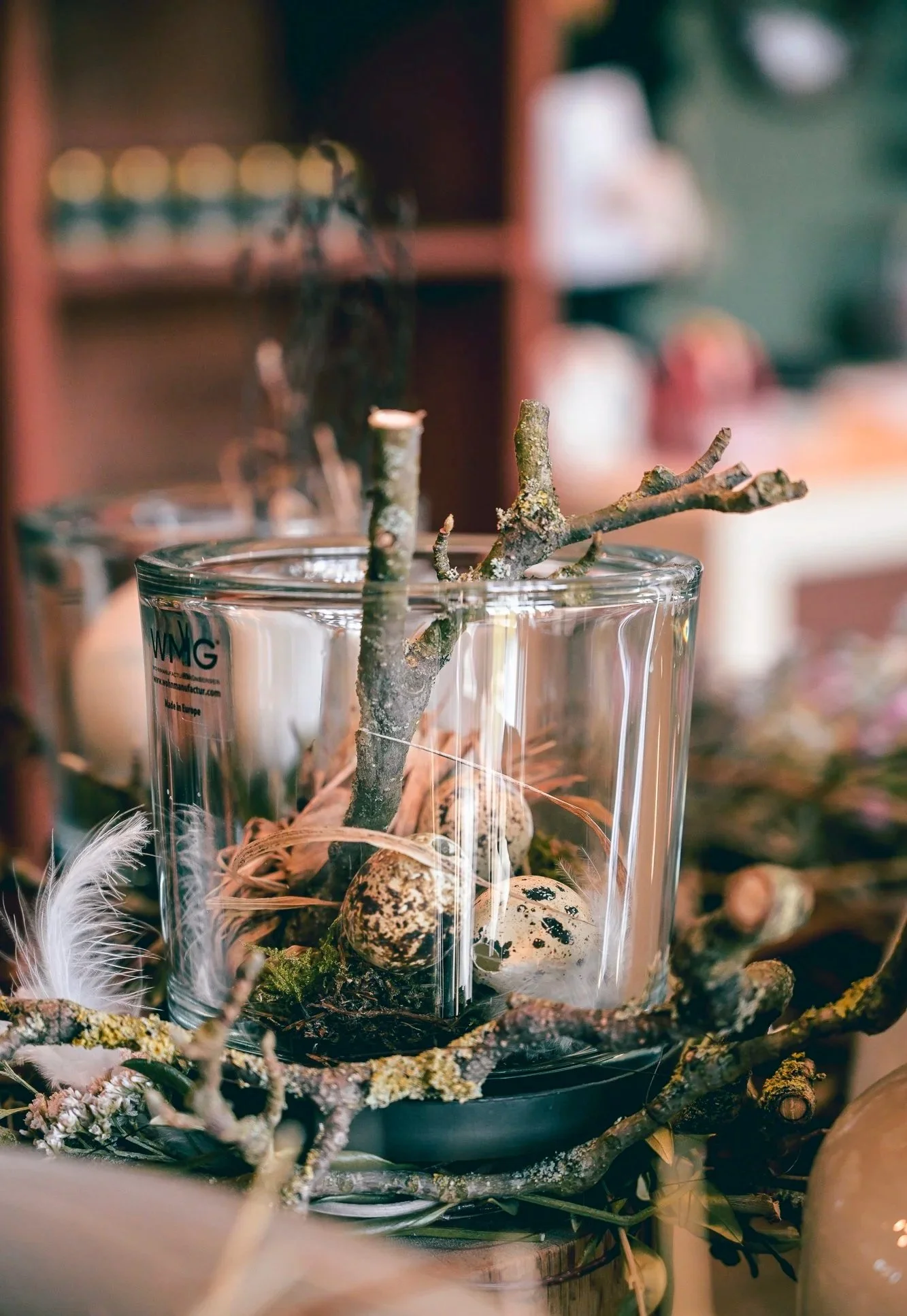 Floristisches Arrangement aus Glas, Holz, Zweigen und Naturmaterialien – Detailaufnahme aus der Blumenbinderei Bachmaier.