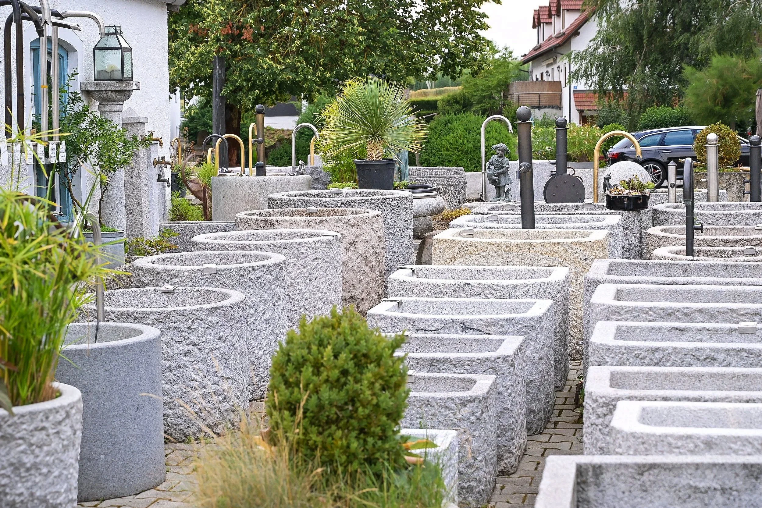 Unternehmensfotografie Czernei Natursteinhandel: Außenausstellung mit Granitbrunnen und Natursteinbecken.