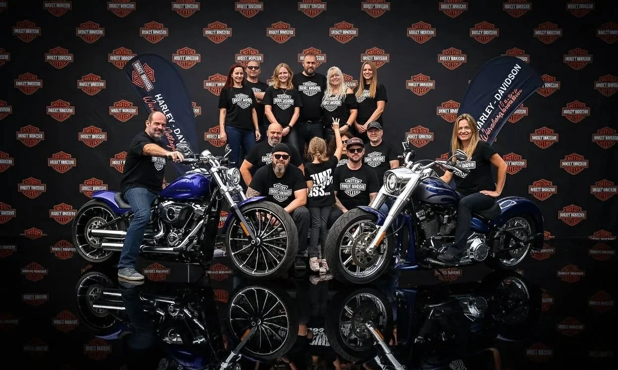 Teamfotografie, Eventfotografie bei Harley-Davidson-Würzburg Village- Team posiert mit zwei Motorrädern vor einer Harley-Davidson-Fotowand.