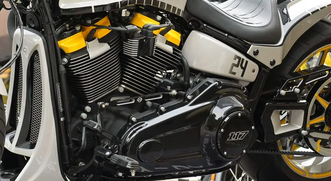 Produktfotografie Harley-Davidson Würzburg Village: Nahaufnahme des schwarzen V-Twin-Motors eines Custom-Motorrads mit gelben Zylinderabdeckungen und der Kennzeichnung „117“