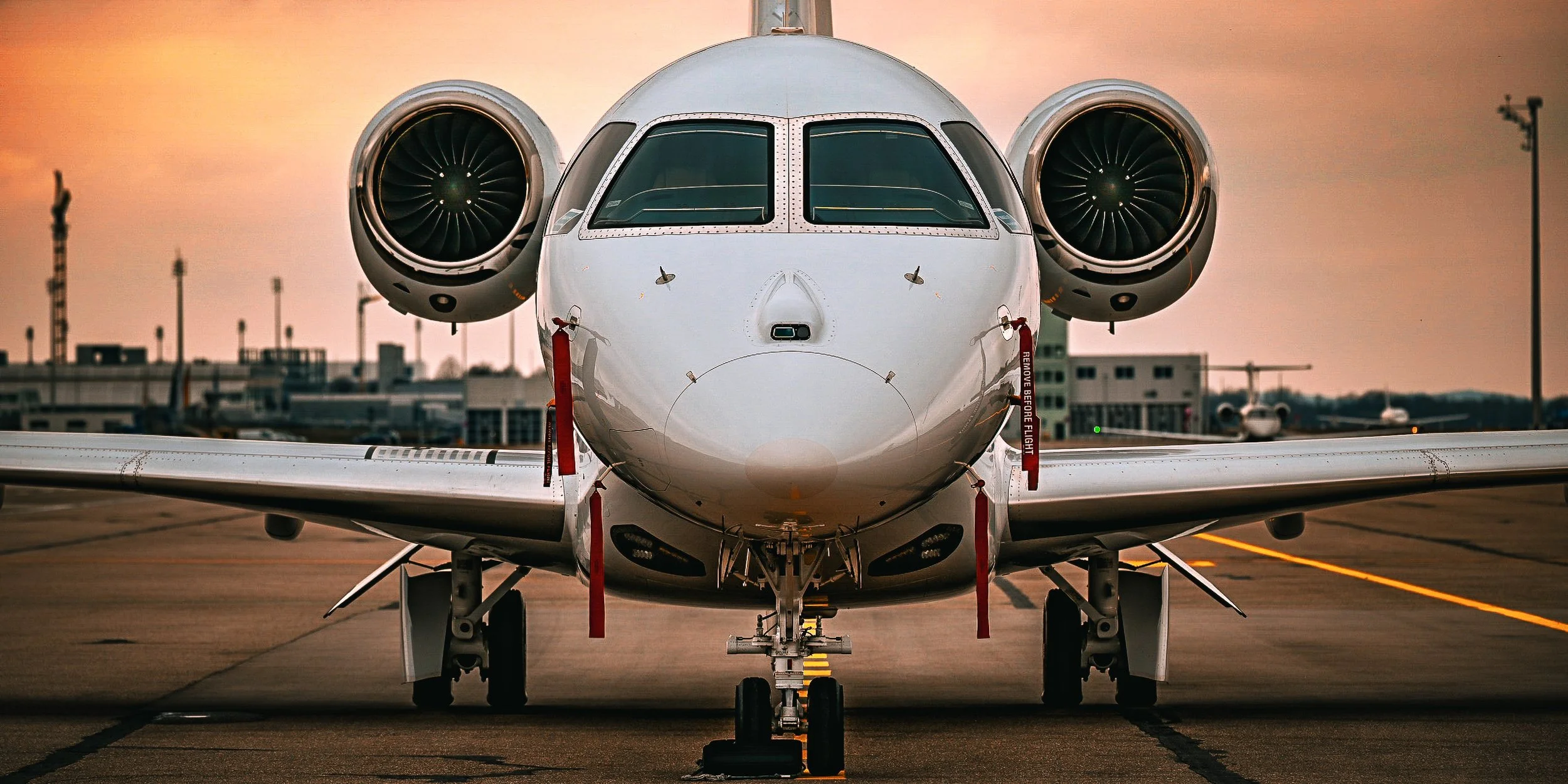 Frontansicht eines zweimotorigen Geschäftsflugzeugs auf einer Start- und Landebahn bei Sonnenuntergang