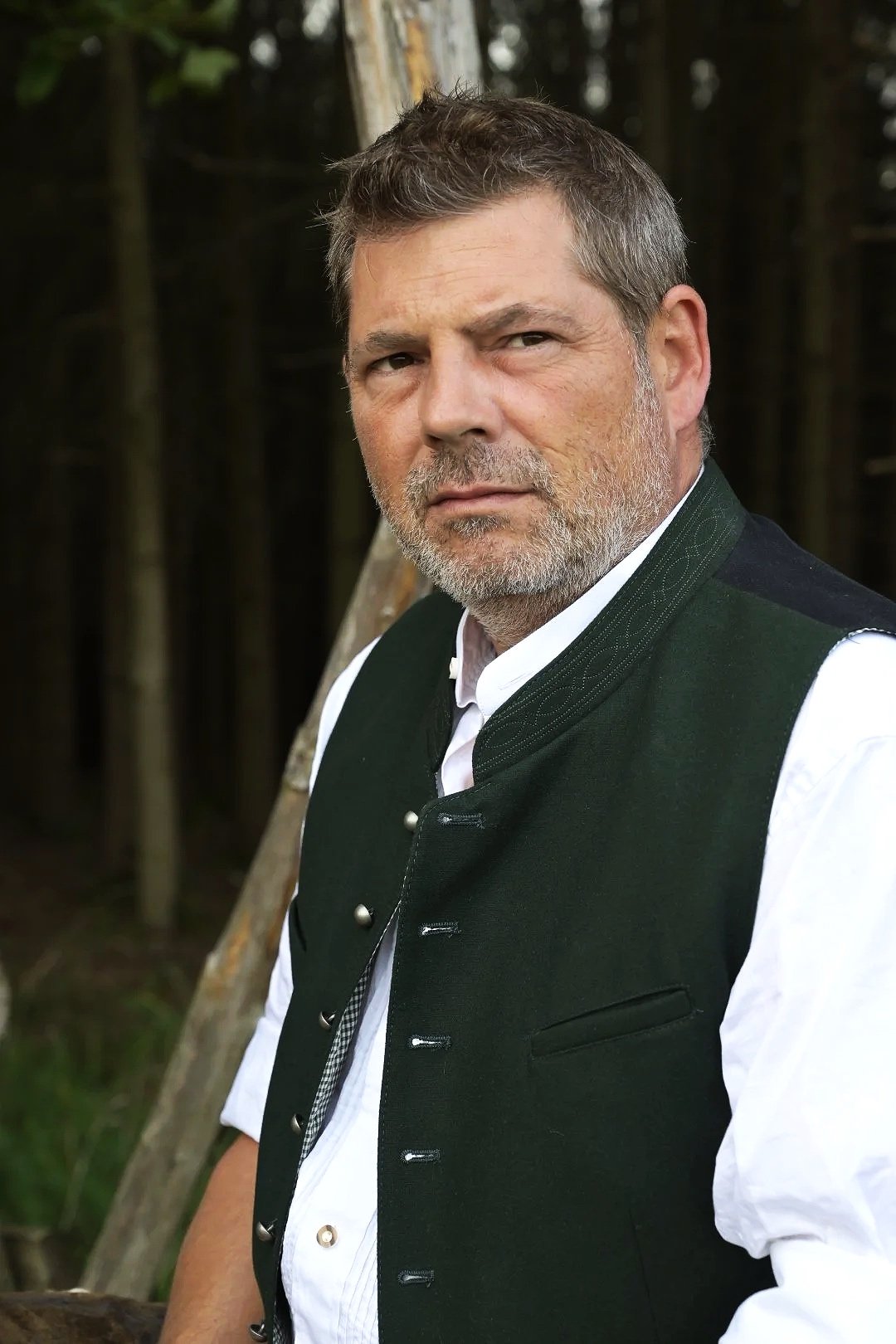 People-Porträt: in traditioneller bayerischer Tracht vor einer Waldkulisse.