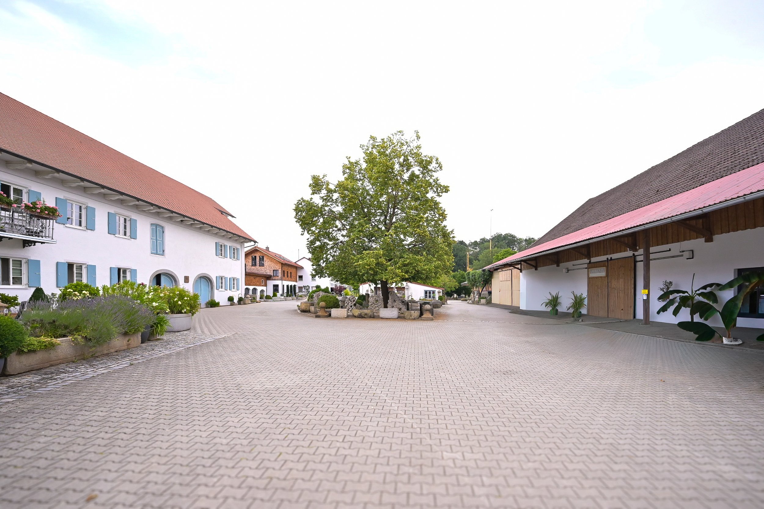 Architektur- und Immobilienfotografie: Gepflasterter Innenhof eines bayerischen Landguts mit historischen Gebäuden.