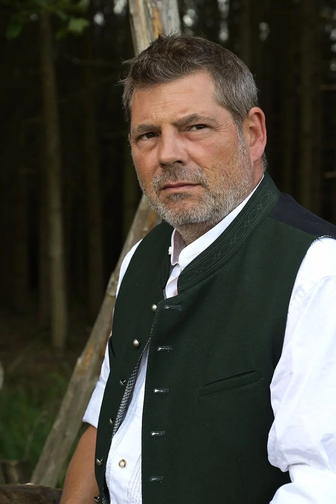 People-Porträt:  in traditioneller bayerischer Tracht vor einer Waldkulisse.