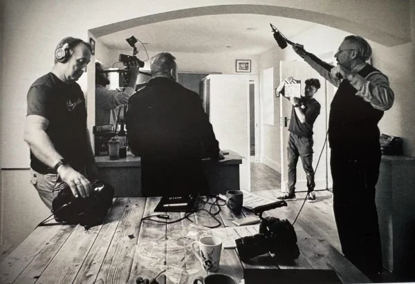 Behind‑the‑scenes moment of a film crew capturing sound and dialogue in a kitchen studio, surrounded by microphones, cameras, and production gear.