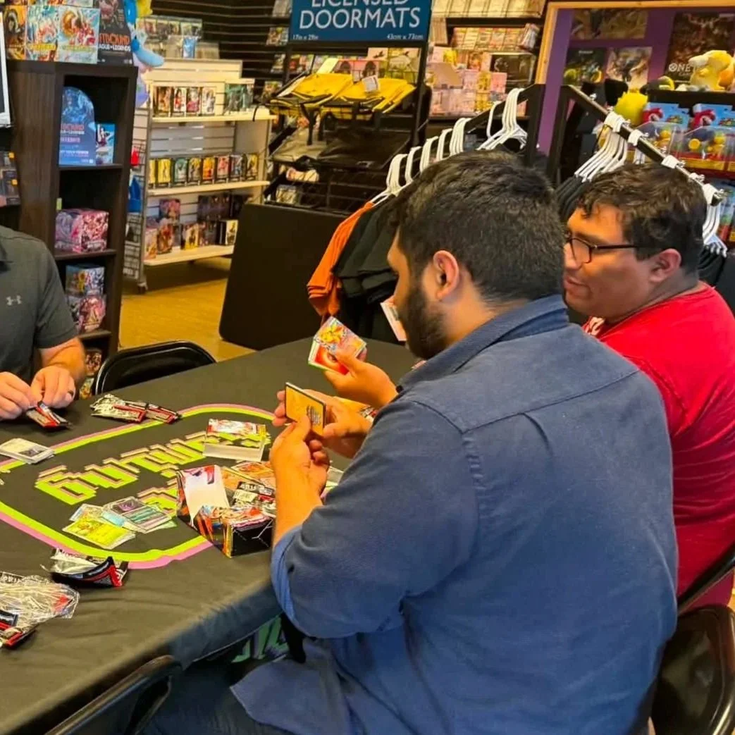 People playing a trading card game at a table inside a comic and game store