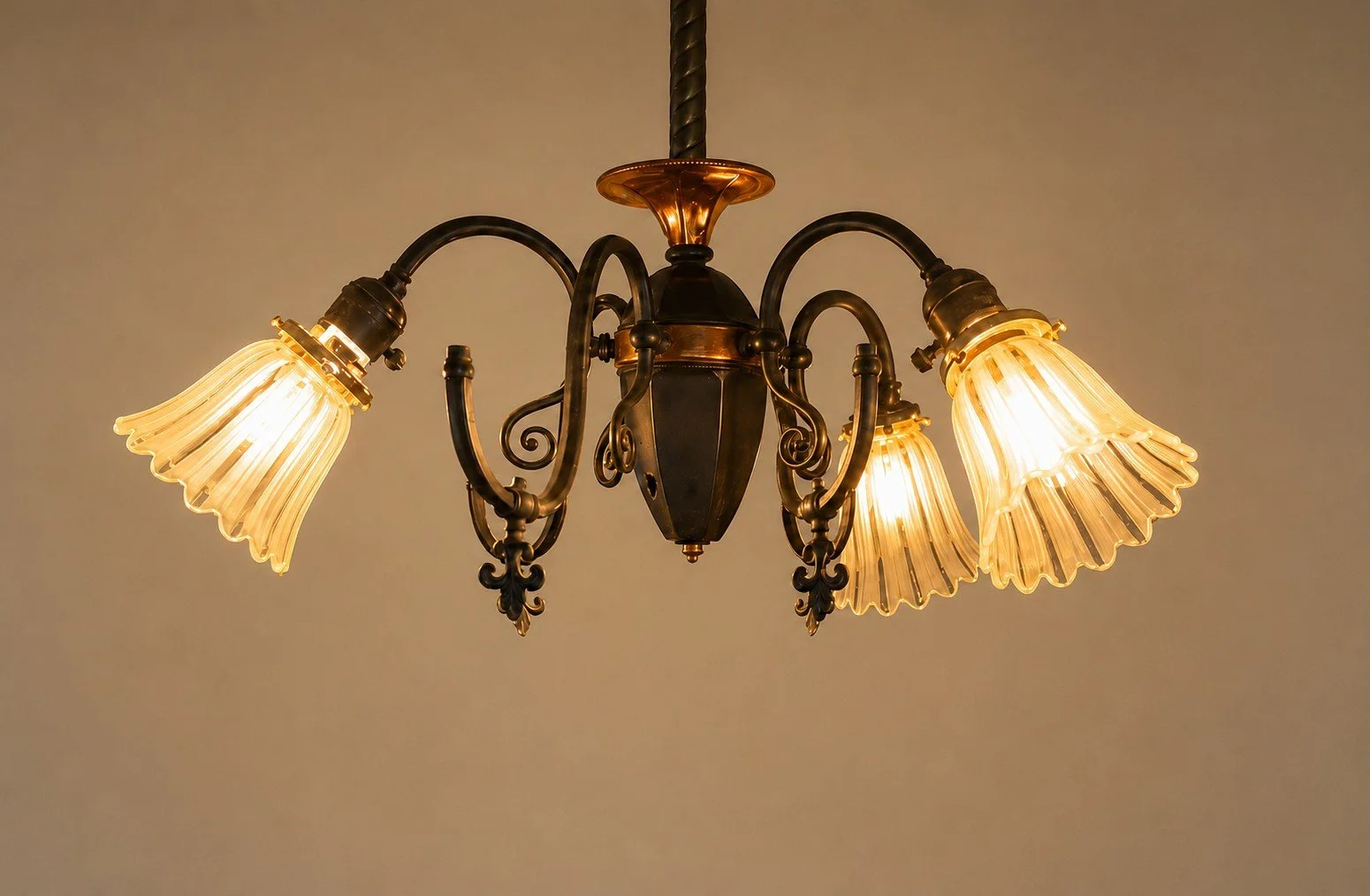 A vintage chandelier with five fabric lampshades hanging from a dark metal frame.