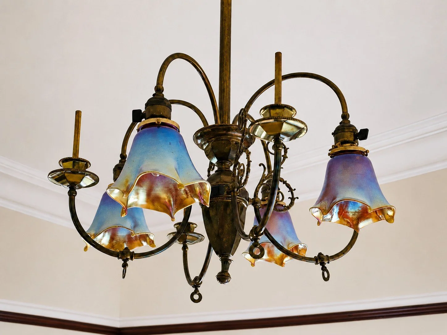 An ornate chandelier with five blue and gold glass shades hanging from a brass fixture.