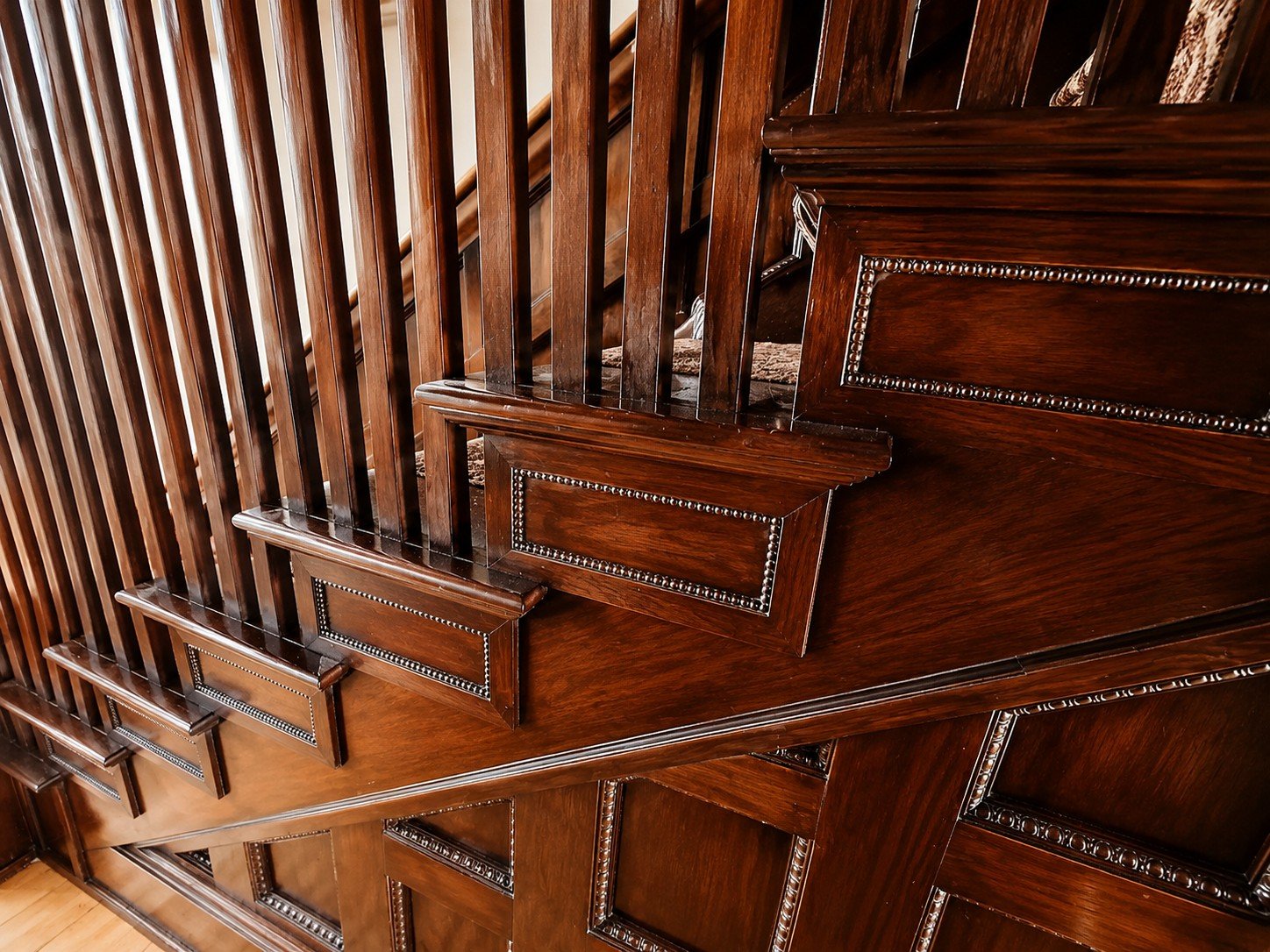 Close-up of a wooden staircase with ornate paneling and a polished finish.