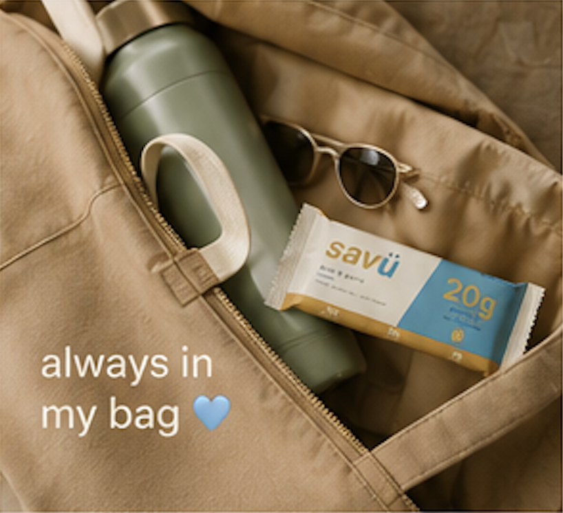 A gym bag containing a green thermos, a pair of sunglasses, and a package of Savü's protein bar with a 20g plant based protein, with the text overlay "always in my bag" and a blue heart emoji.